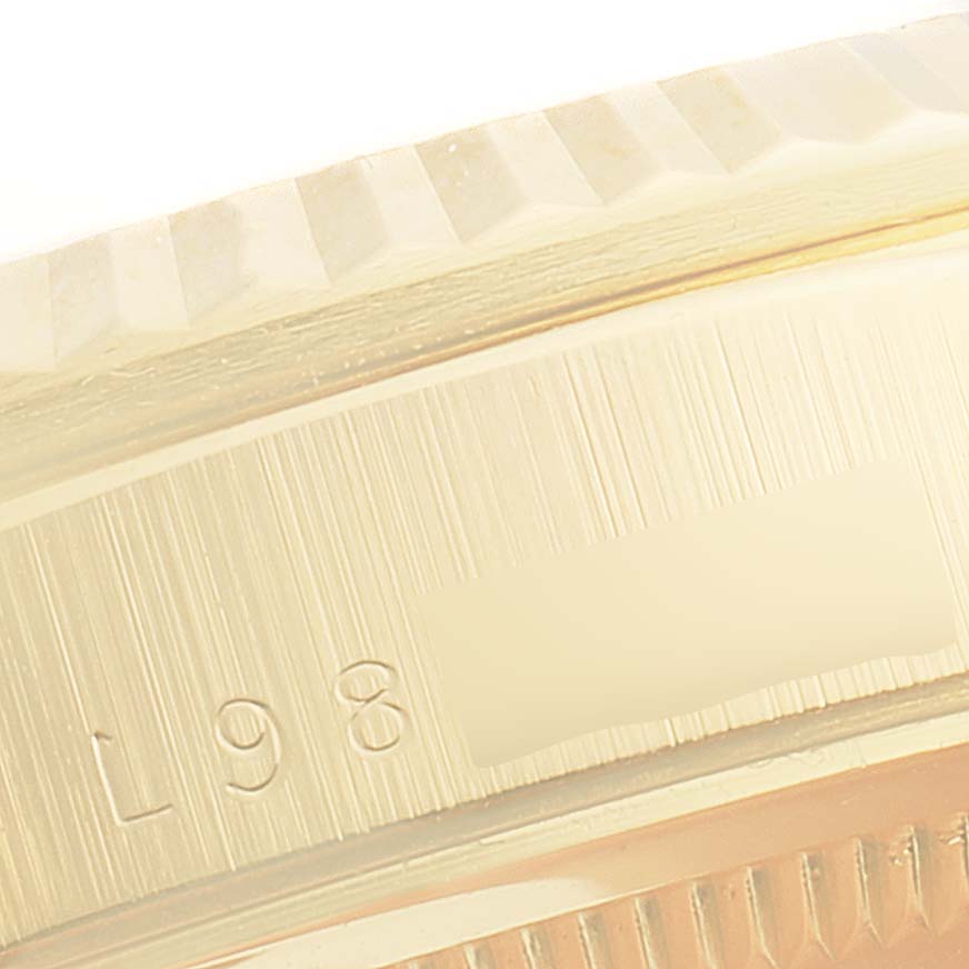 This close-up image of a Rolex President 18238 Men's Yellow Gold Beige Dial 18238 Men's Yellow Gold Beige Dial watch shows part of the bezel and the engraved serial number on the case.