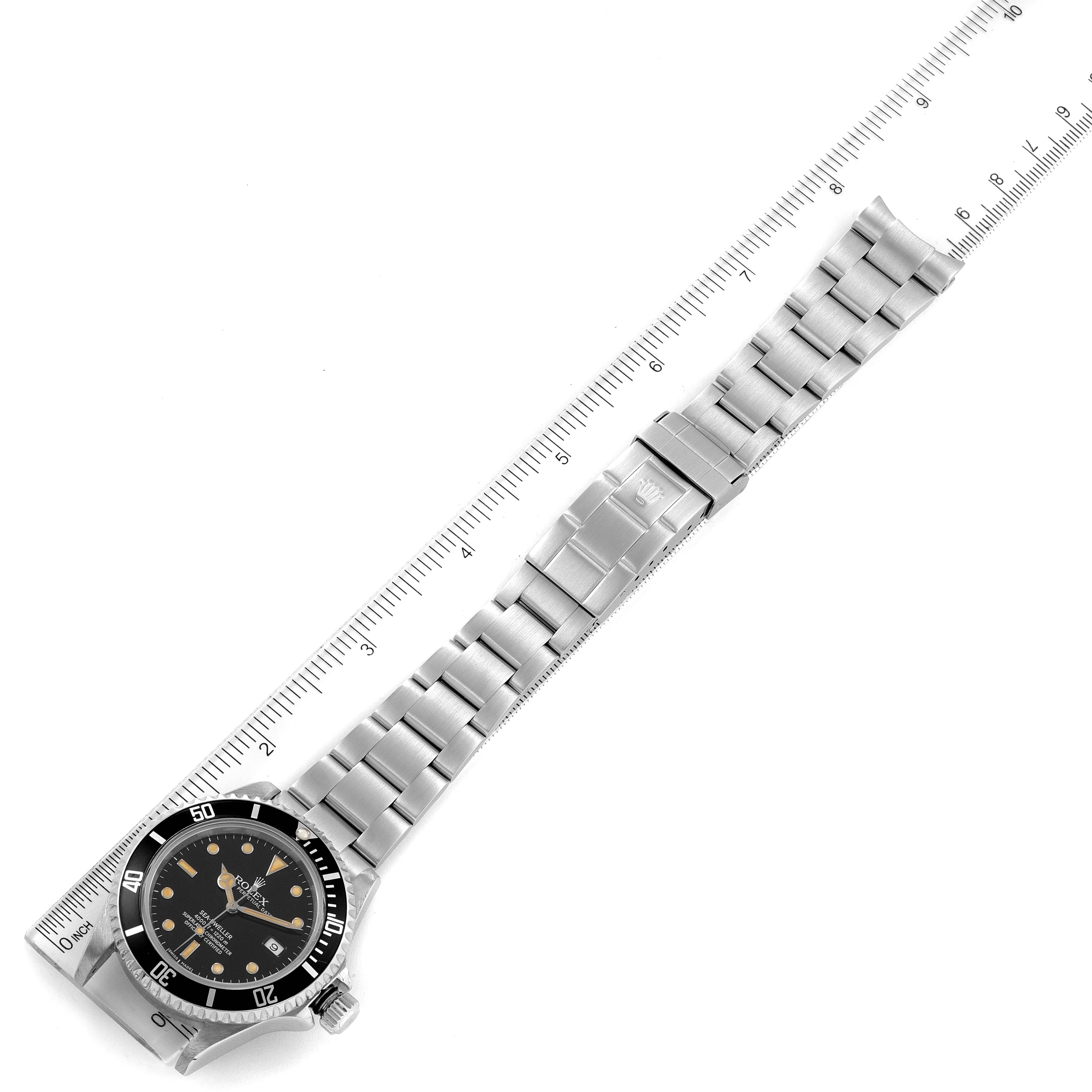 The Rolex Sea-Dweller 16600 Men
s Stainless Steel Black Dial 16600 Men
s Stainless Steel Black Dial watch is shown from an angled top-down view, alongside a ruler, displaying the face and stainless steel bracelet.