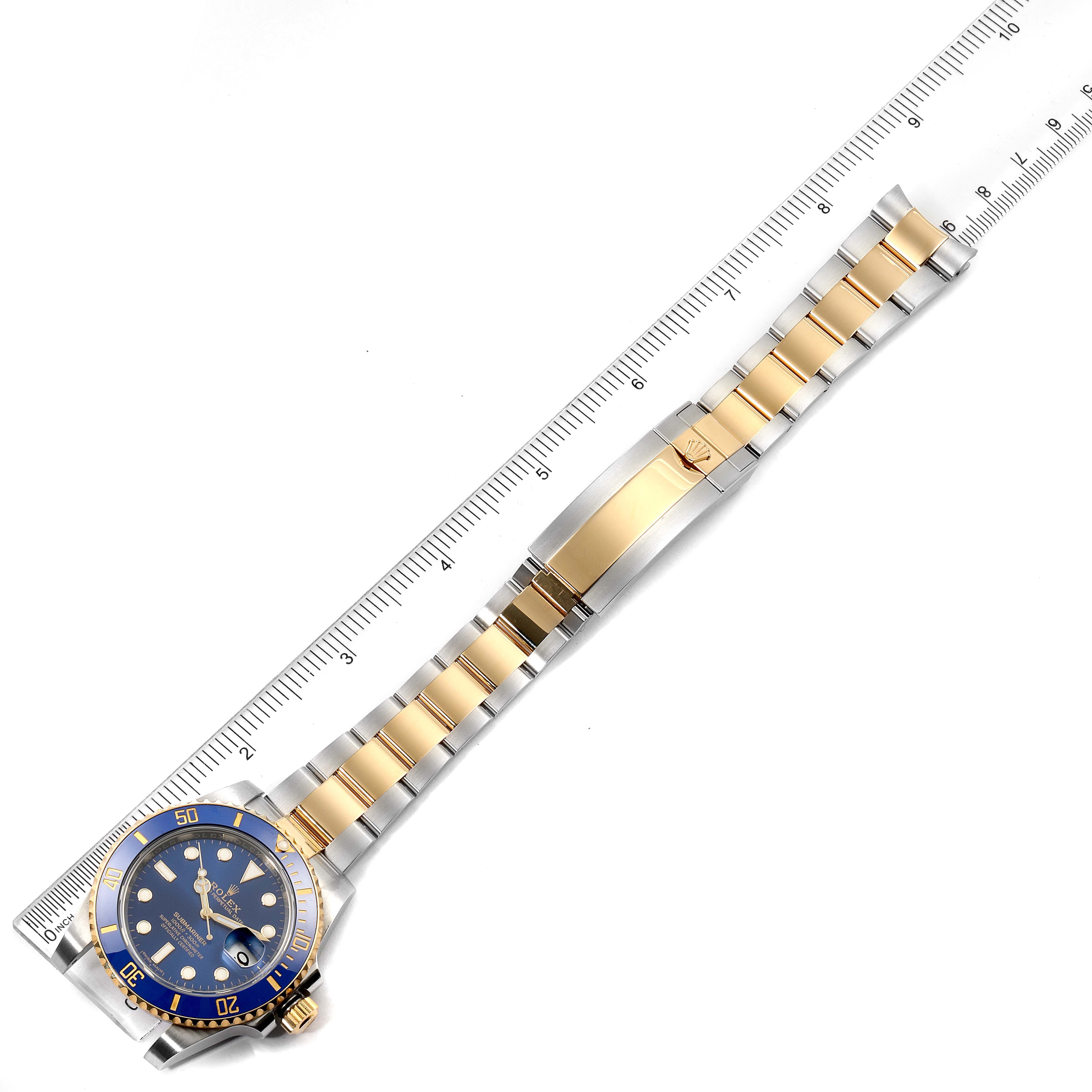 This image shows a top-down view of a Rolex Submariner 116613 Men's Steel and Gold (two tone) Blue Dial 116613 Men's Steel and Gold (two tone) Blue Dial watch with a blue face and two-tone bracelet beside a ruler.
