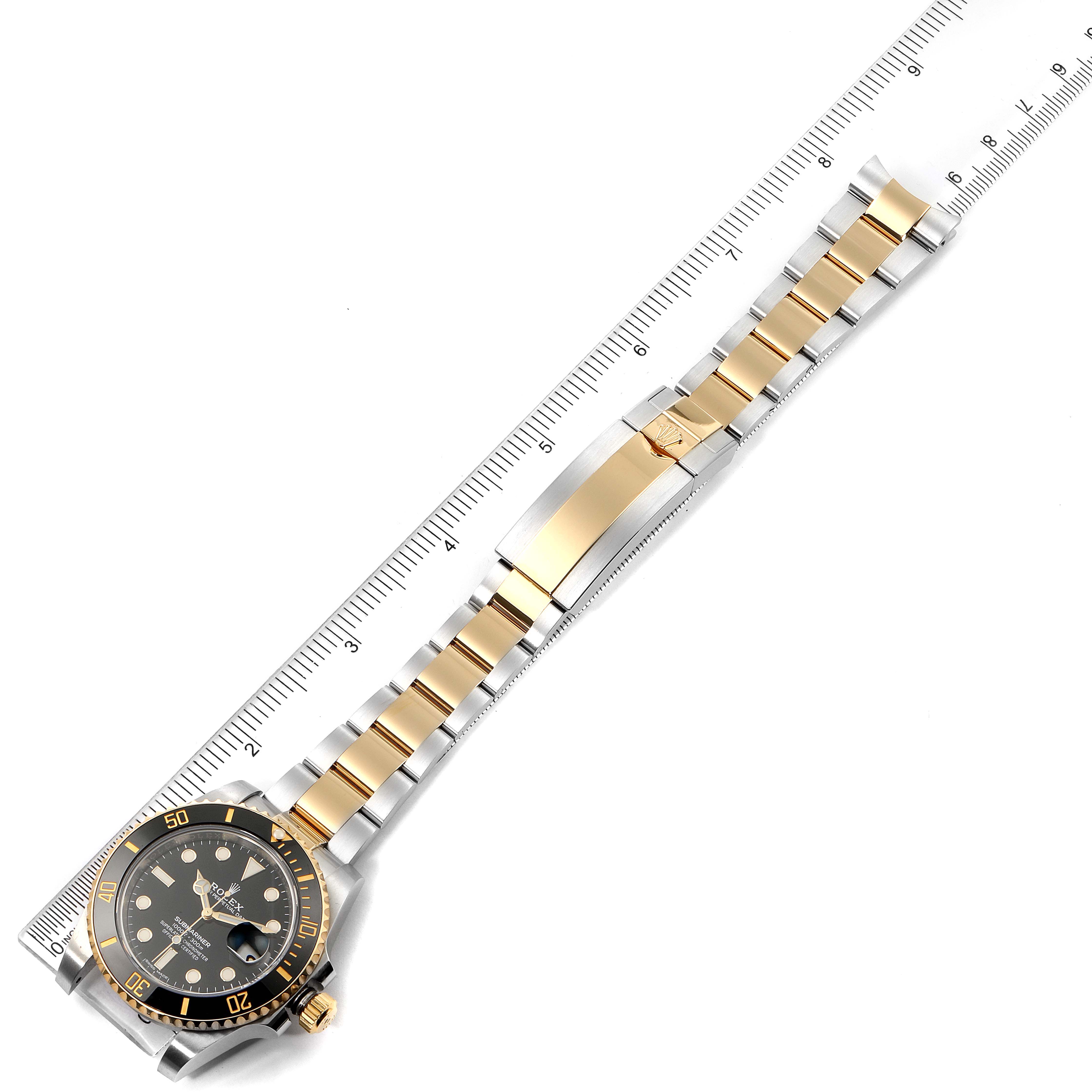 The Rolex Submariner 116613 Men
s Steel and Gold (two tone) Black Dial 116613 Men
s Steel and Gold (two tone) Black Dial watch is shown from an overhead angle, displaying its face, bezel, bracelet, and clasp.