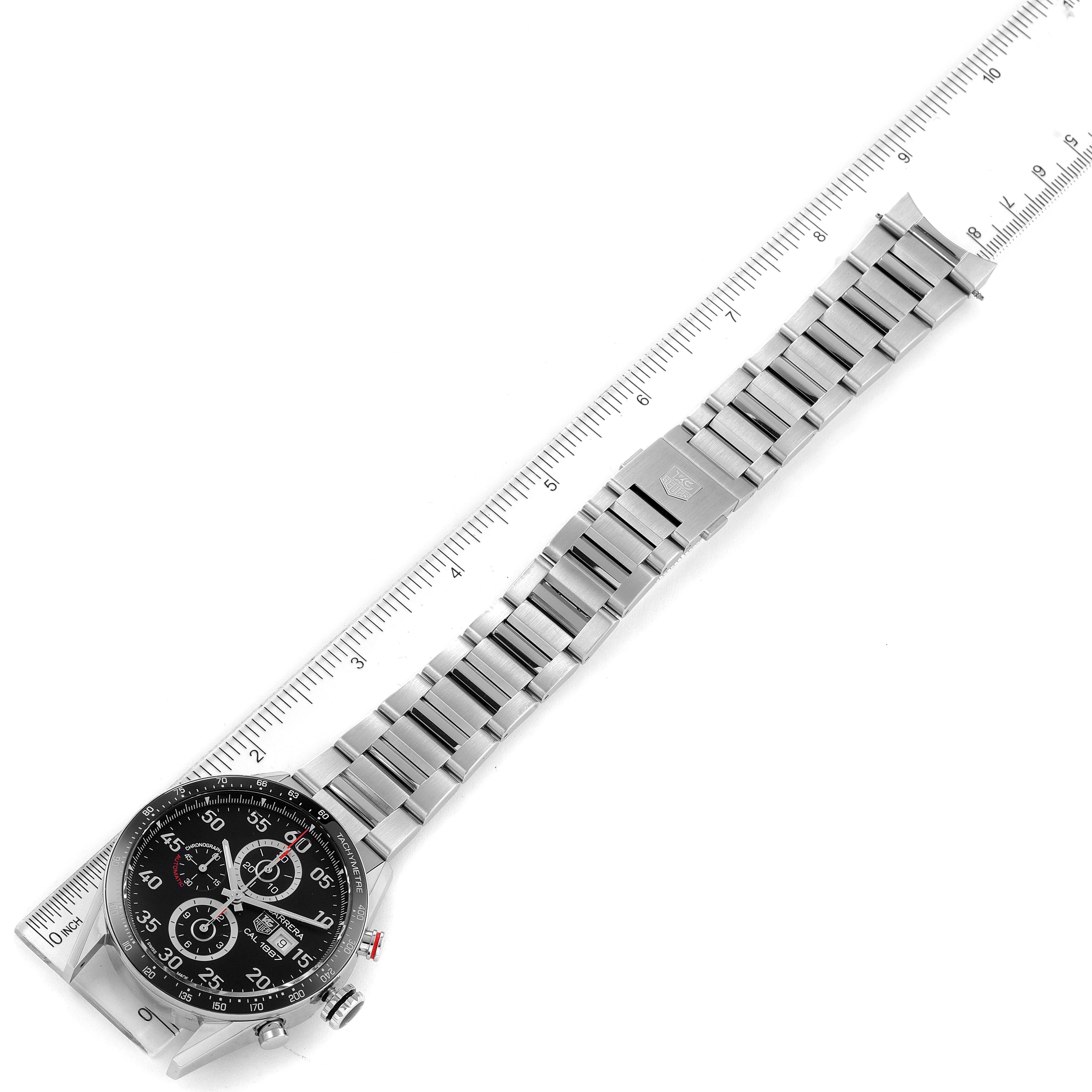 The image shows a top-down view of a Tag Heuer Carrera CAR2A10.BA0799 Men
s Stainless Steel Black Dial CAR2A10.BA0799 Men
s Stainless Steel Black Dial watch with its stainless steel strap fully extended alongside a ruler.