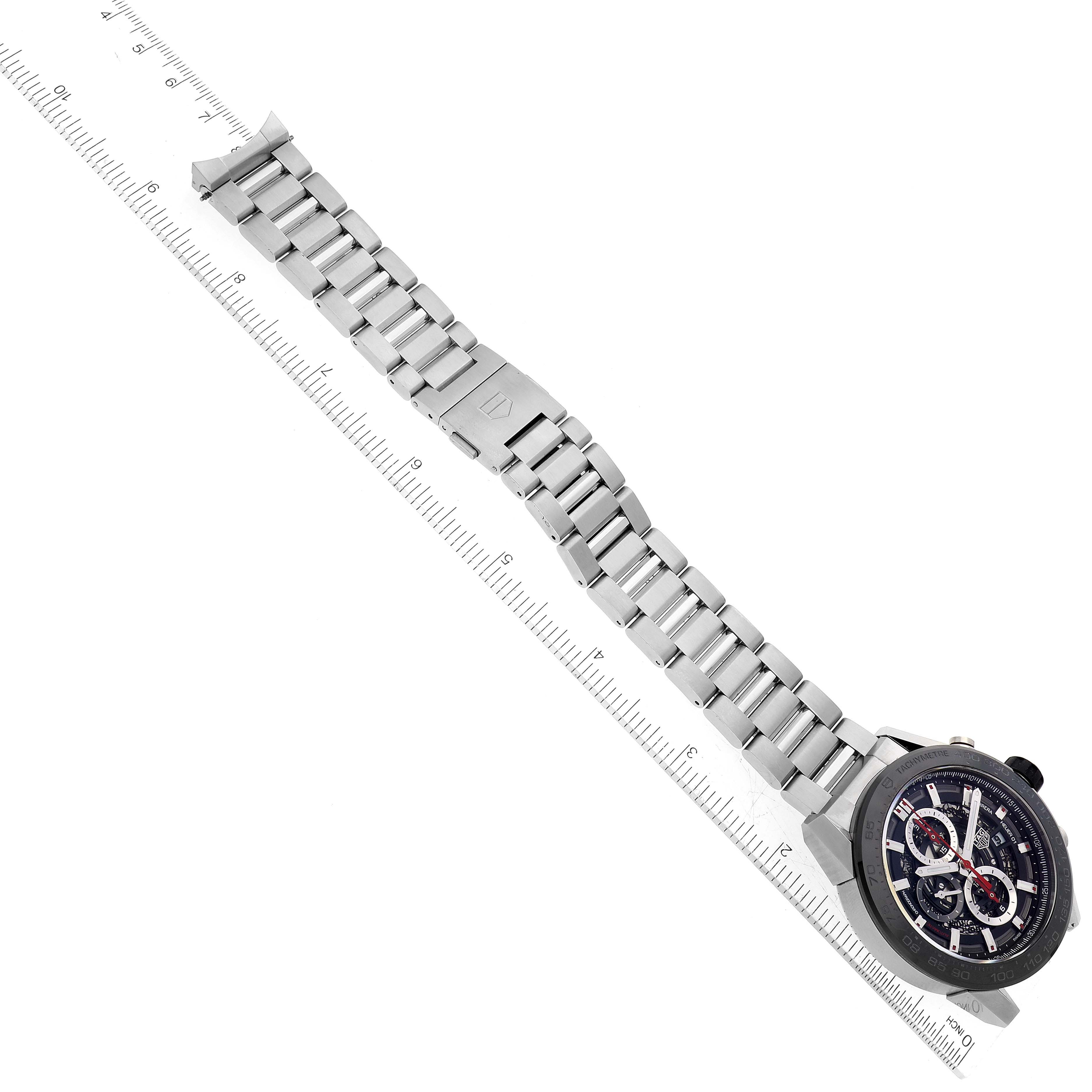 This image shows a Tag Heuer Carrera CAR2A1W.BA0703 Men's Stainless Steel Transparent Dial CAR2A1W.BA0703 Men's Stainless Steel Transparent Dial watch laid out flat with its metal band fully extended next to a ruler for measurement.