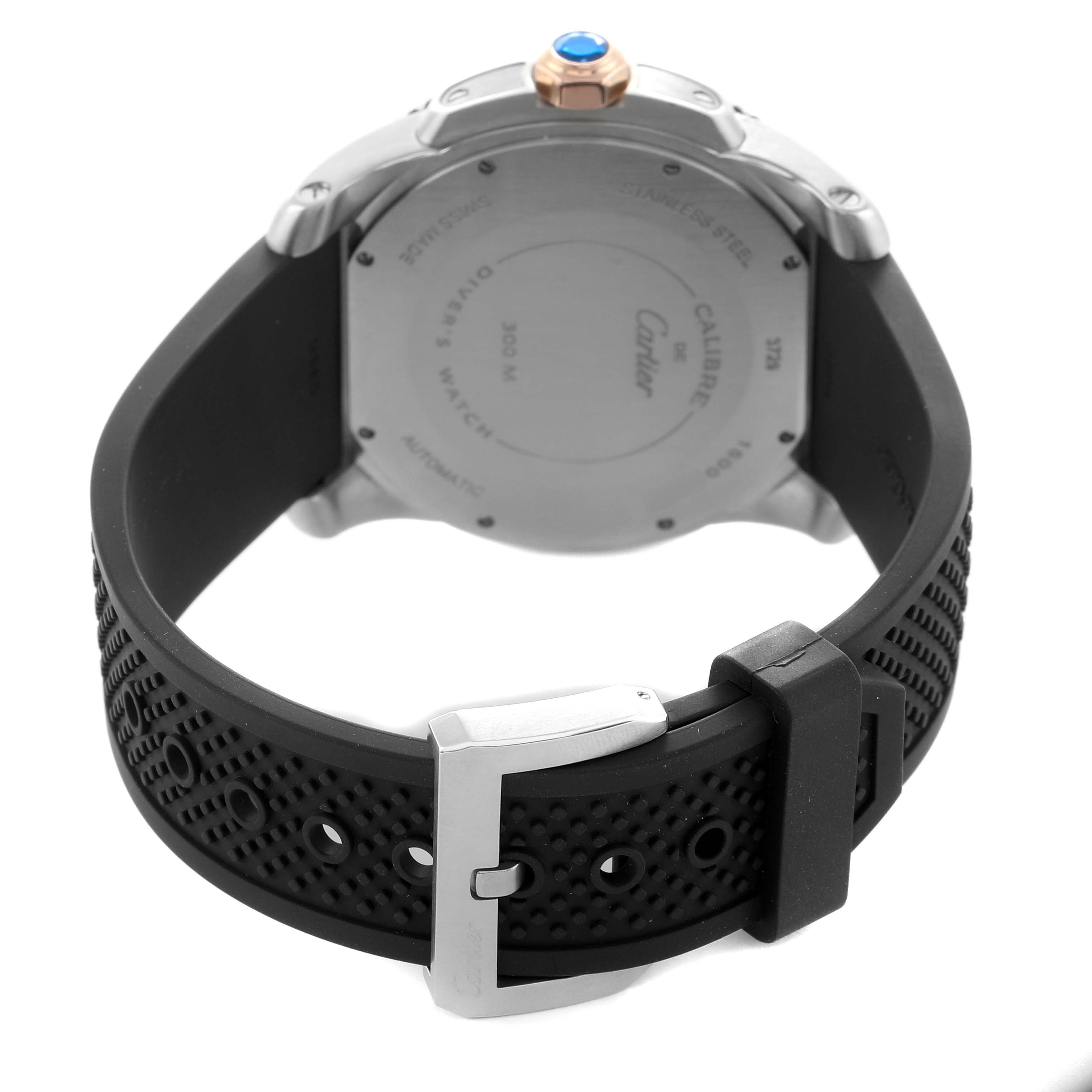 The image shows the back of a Calibre de Cartier watch by Cartier, focusing on the case back, crown, and black rubber strap.