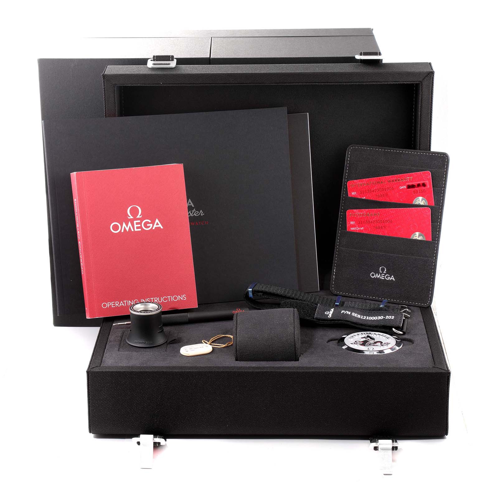The image shows accessories and packaging for an Omega Speedmaster 311.30.42.30.01.006 Men
s Stainless Steel Black Dial 311.30.42.30.01.006 Men
s Stainless Steel Black Dial, including manuals, cards, and tools, all within an open box.