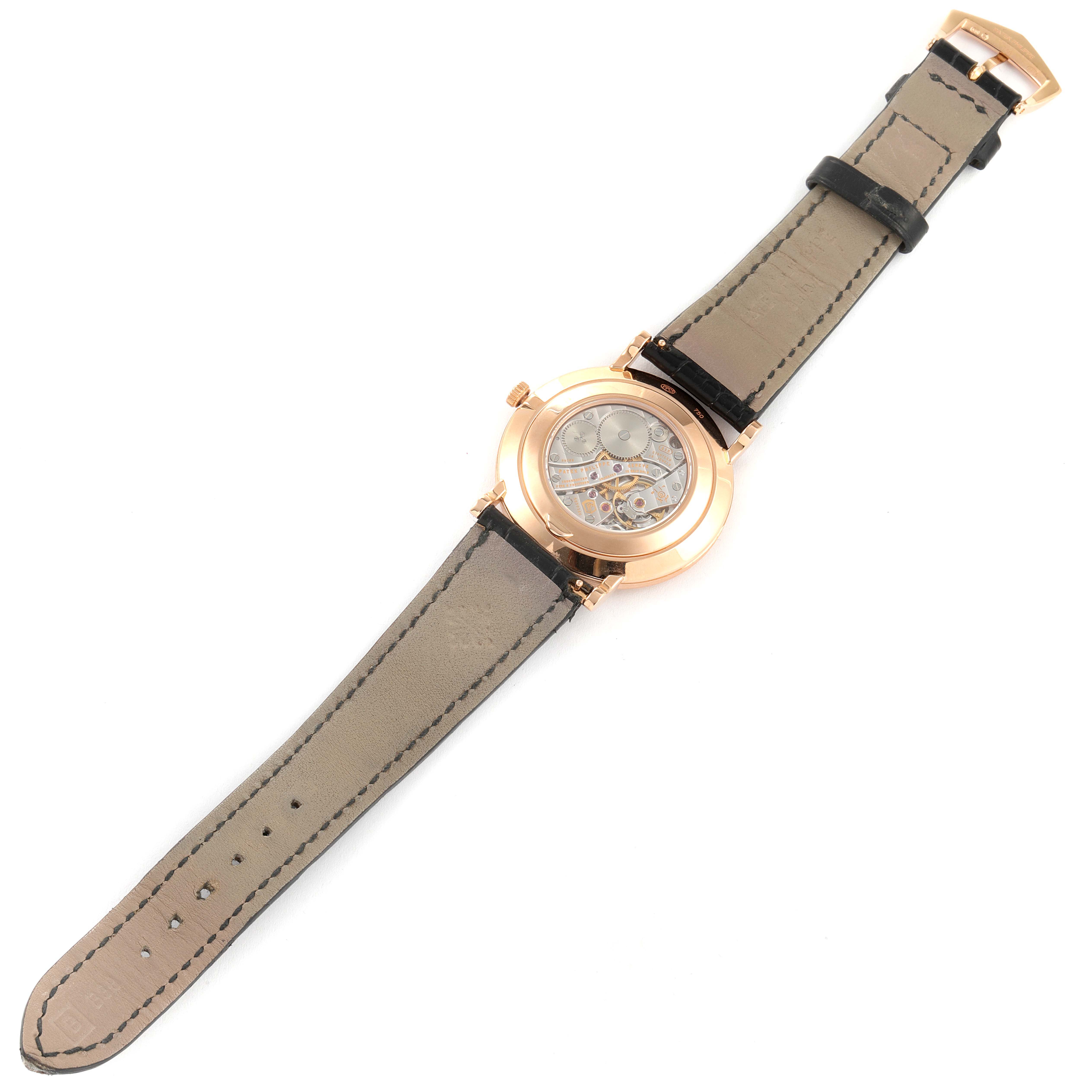 The image shows a Patek Philippe Calatrava 5119R Men's Rose Gold White Dial 5119R Men's Rose Gold White Dial watch from the back, highlighting the leather strap and the transparent case back revealing the movement.