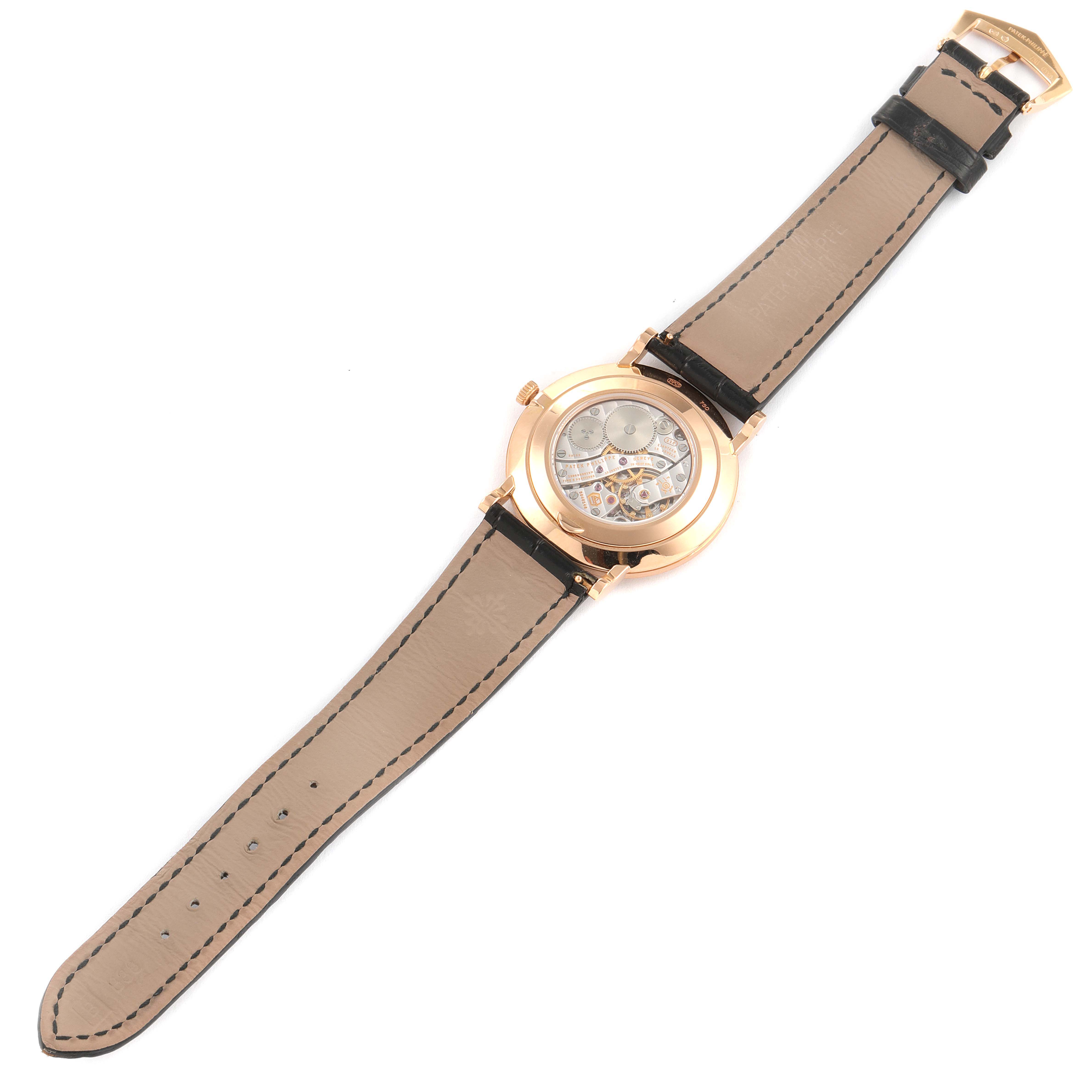 The image shows the back view of a Patek Philippe Calatrava 5119R Men's Rose Gold White Dial 5119R Men's Rose Gold White Dial watch, highlighting its leather strap and transparent case back revealing the movement.