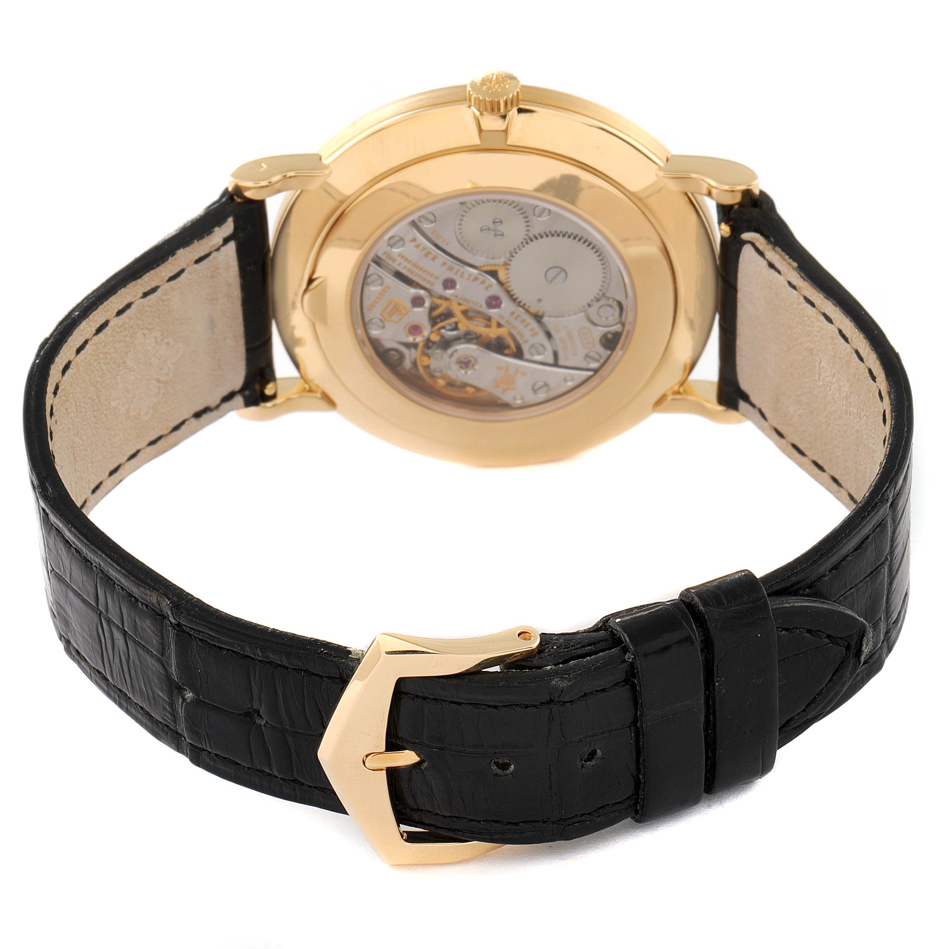 The image shows the back view of the Calatrava watch by Patek Philippe, displaying its mechanical movement and black leather strap.