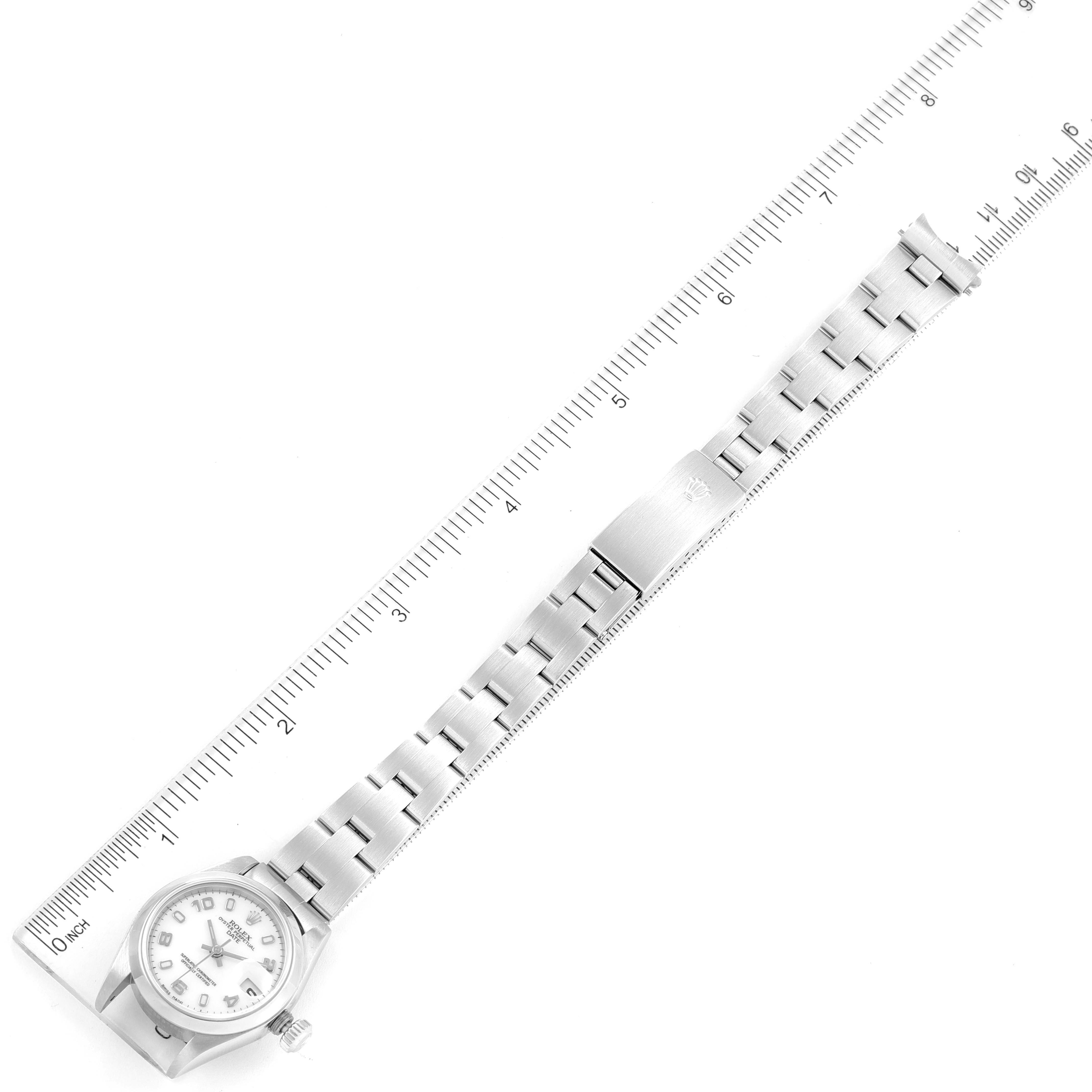 This image shows a top-down view of a Rolex Date 79160 Women's Stainless Steel White Dial 79160 Women's Stainless Steel White Dial model watch with its full bracelet and clasp, alongside a ruler for scale.