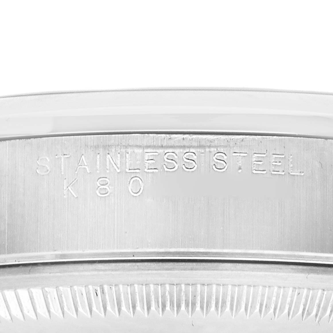 The image shows a close-up of the engraved edge of a Rolex Date 15200 Men's Stainless Steel Silver Dial watch case, highlighting the "STAINLESS STEEL" text.
