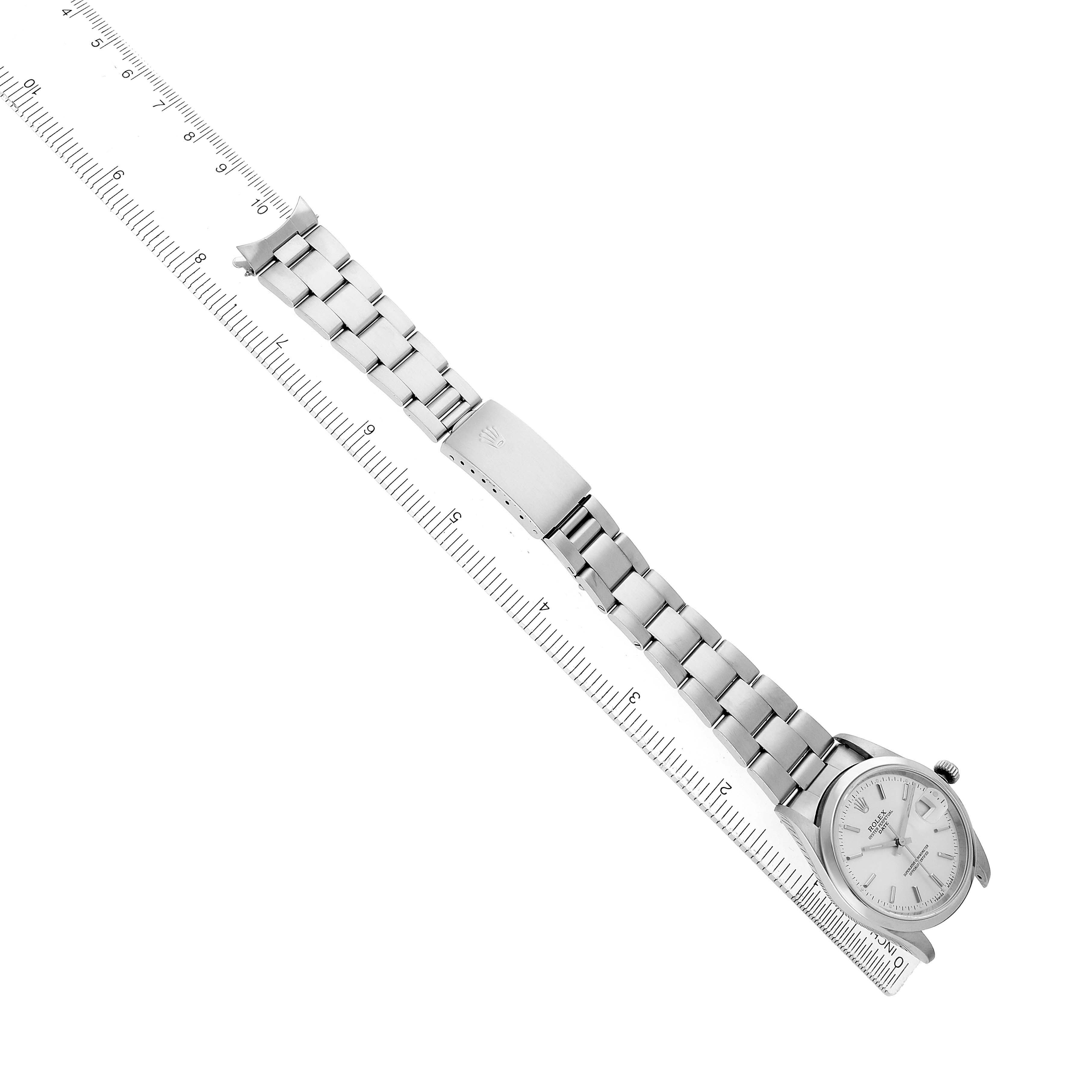 The Rolex Date 15200 Men's Stainless Steel Silver Dial watch is shown from an angled top view, highlighting the band and face, with a ruler for scale.