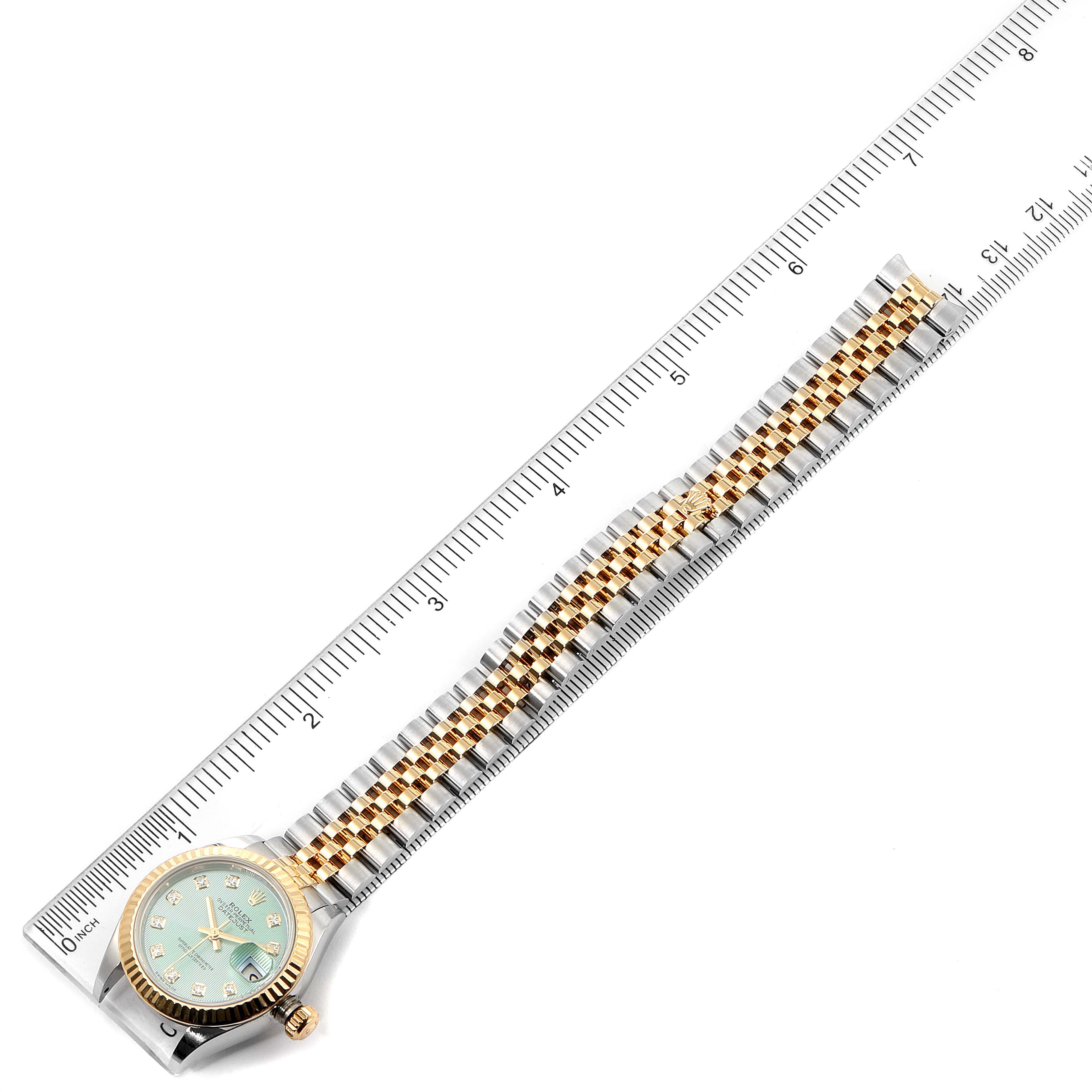 The Datejust model by Rolex is shown from a top-down angle, displaying its face, bezel, and bracelet, alongside a ruler for scale.