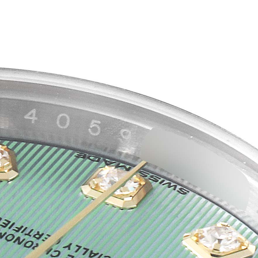 This close-up of the Rolex Datejust 279173 Women's Steel and Gold (two tone) Green Dial 279173 Women's Steel and Gold (two tone) Green Dial watch shows its dial with diamond hour markers and part of the date wheel.