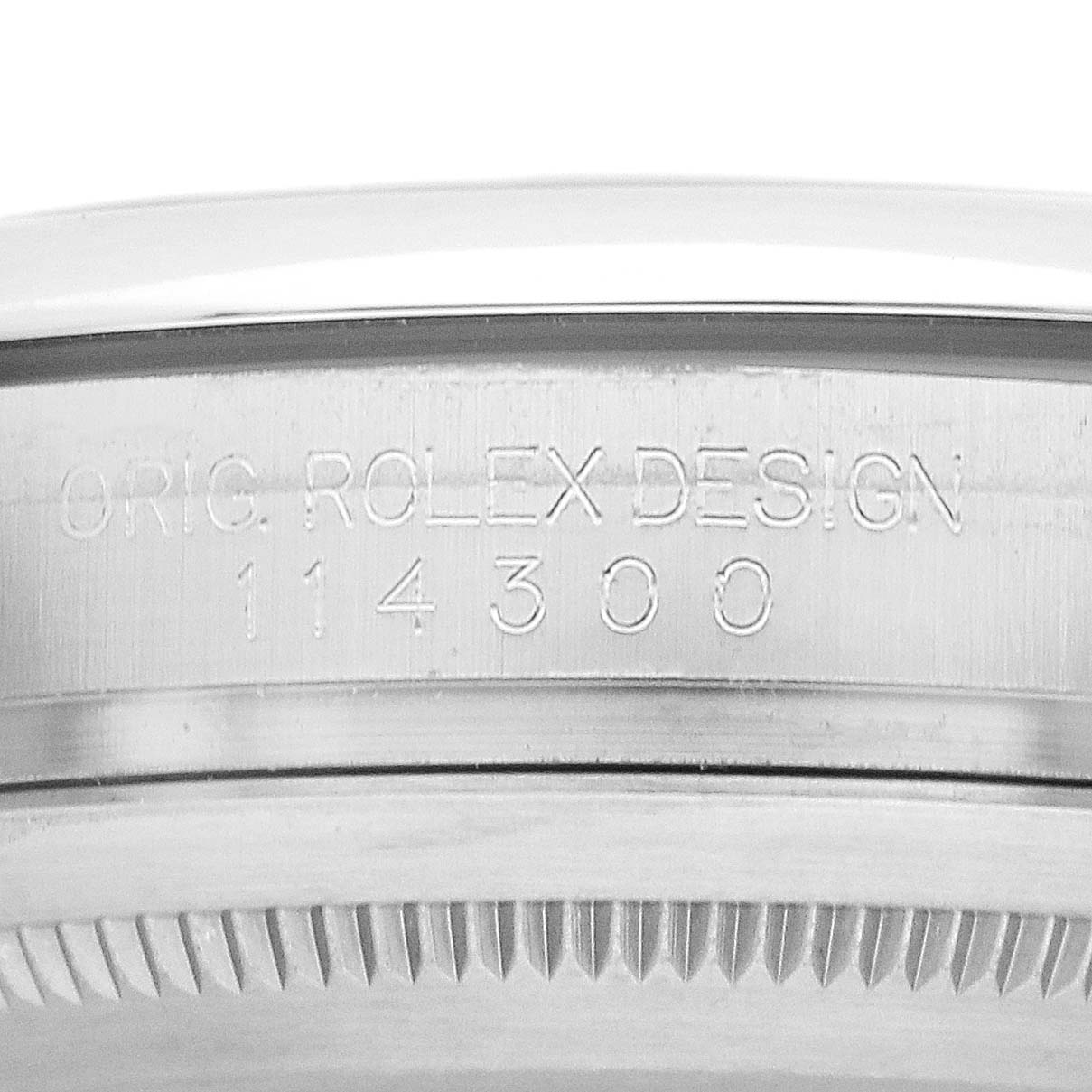 The image shows a close-up of the engraved side of the Rolex Oyster Perpetual 114300 Men's Stainless Steel Blue Dial's case with model number.