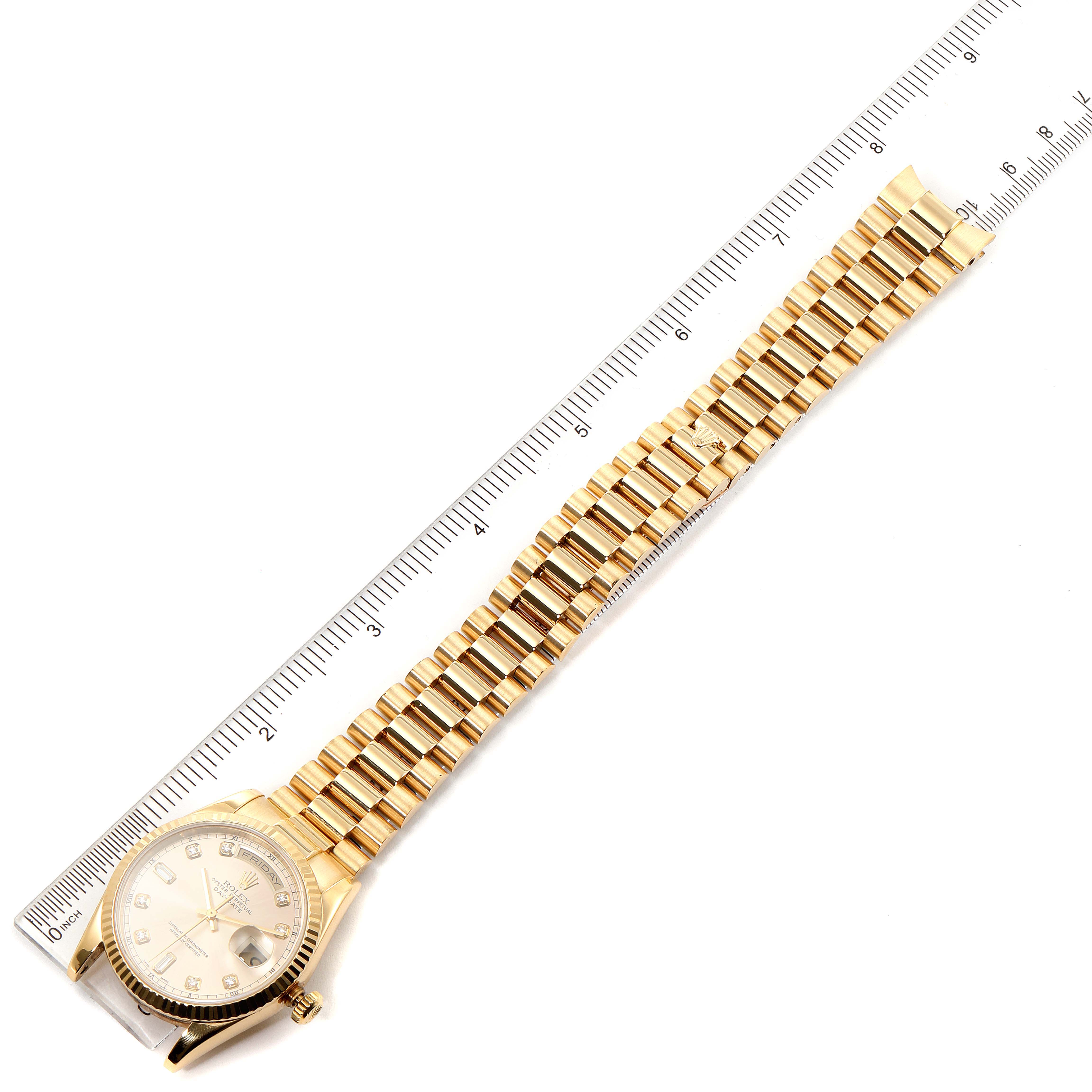 The image shows a top view of a Rolex President 118238 Men
s Yellow Gold Champagne Dial 118238 Men
s Yellow Gold Champagne Dial model watch with its full gold bracelet and part of a ruler for scale.