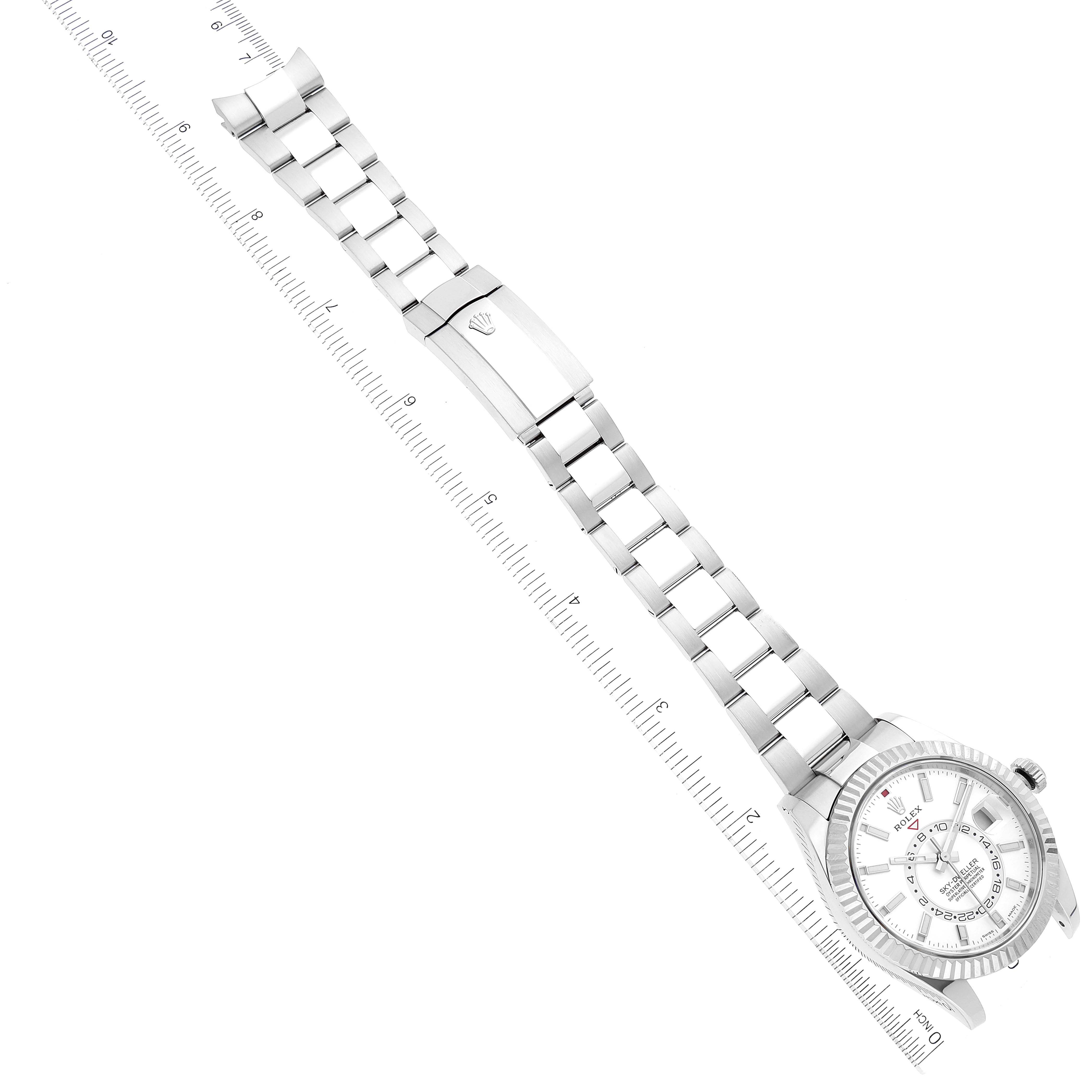 The Rolex Sky-Dweller 326934 Men's Stainless Steel White Dial 326934 Men's Stainless Steel White Dial watch is shown laid flat with a ruler, displaying the face, band, and clasp.