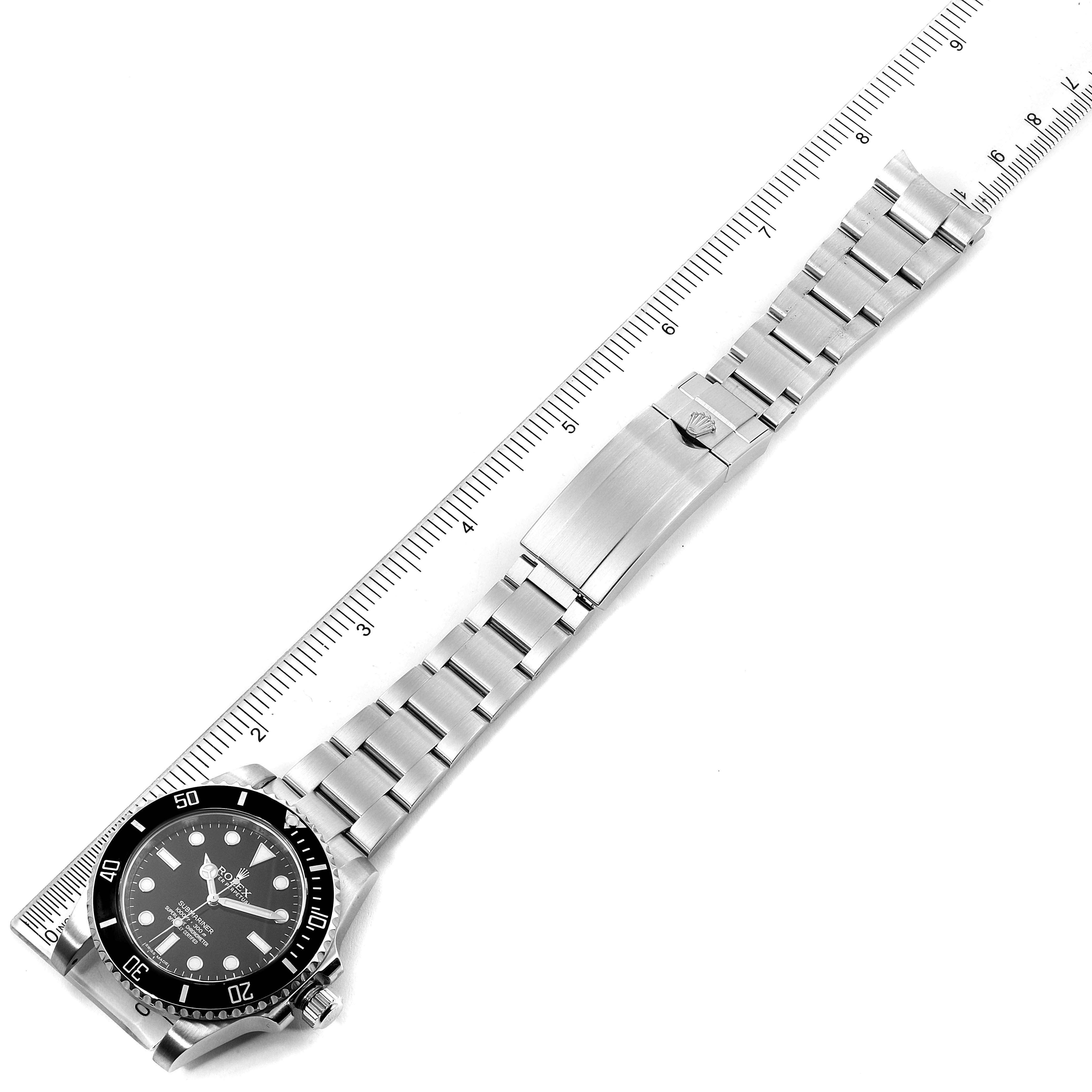 The image shows a Rolex Submariner 114060 Men
s Stainless Steel Black Dial 114060 Men
s Stainless Steel Black Dial watch placed flat with its bracelet extended alongside a ruler for measurement.