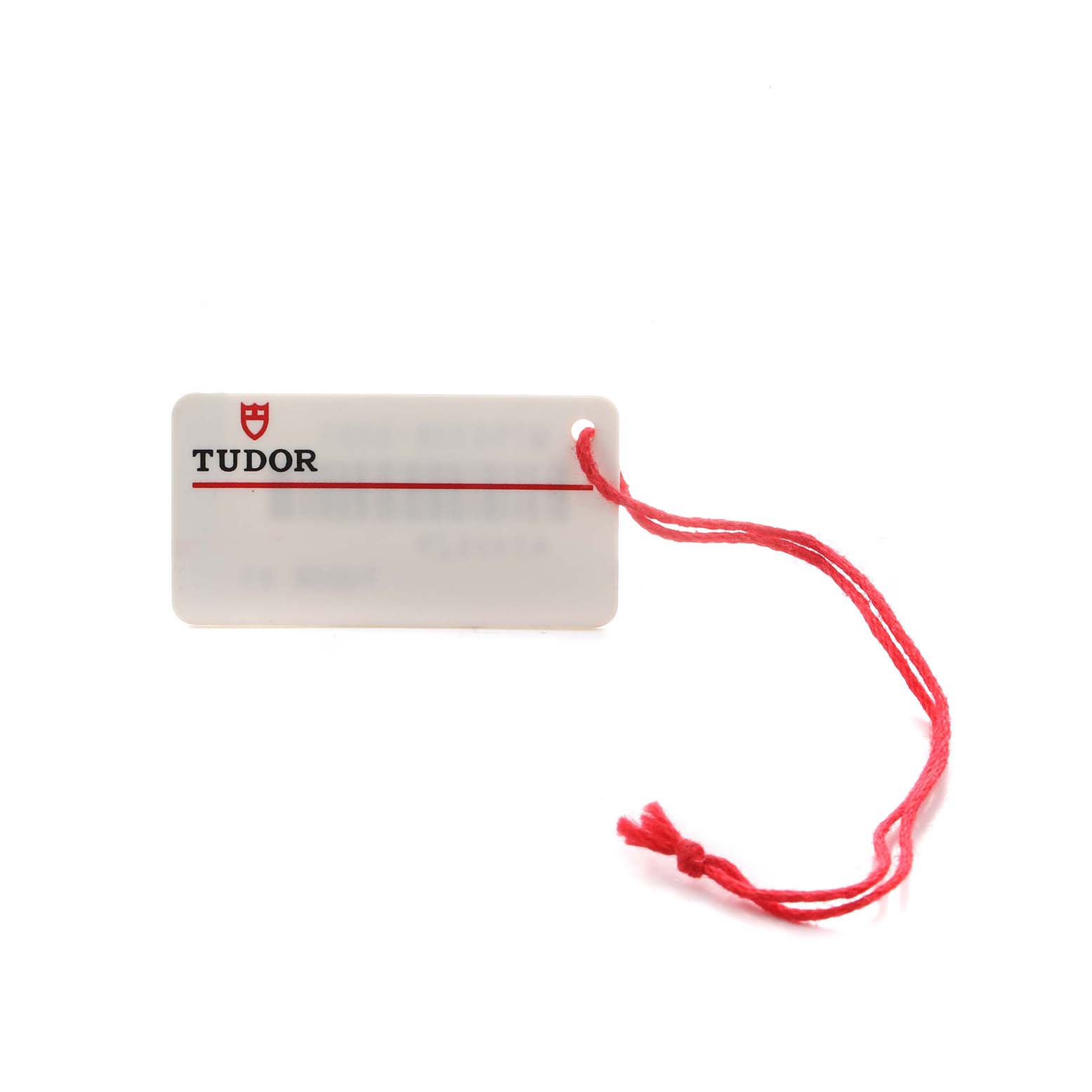 The image shows a Tudor tag with a red string, likely an accessory for the Heritage Black Bay watch.