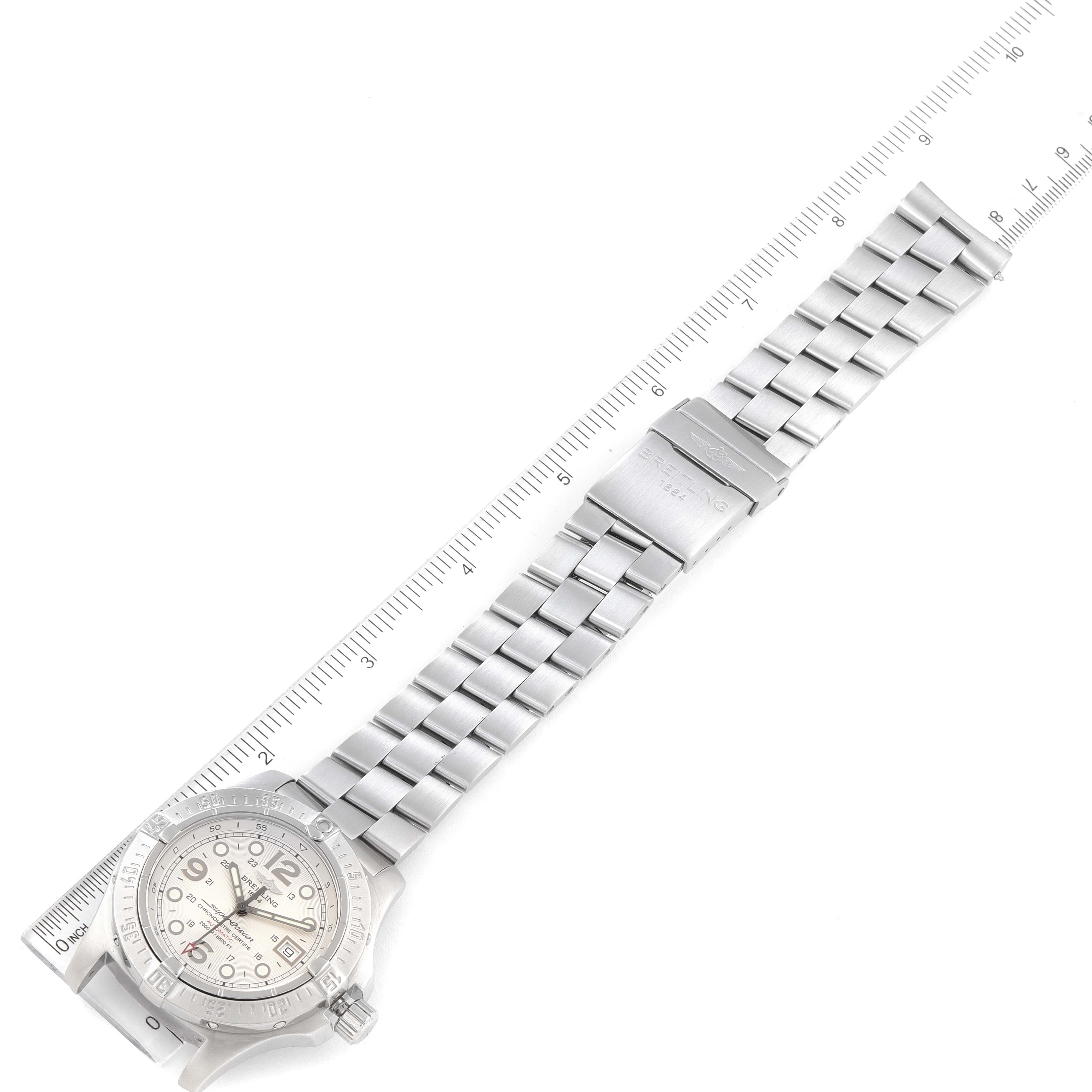 The image shows a top-down view of the Breitling Superocean A17390 Men's Stainless Steel Silver Dial A17390 Men's Stainless Steel Silver Dial watch with its stainless steel bracelet fully extended alongside a ruler.