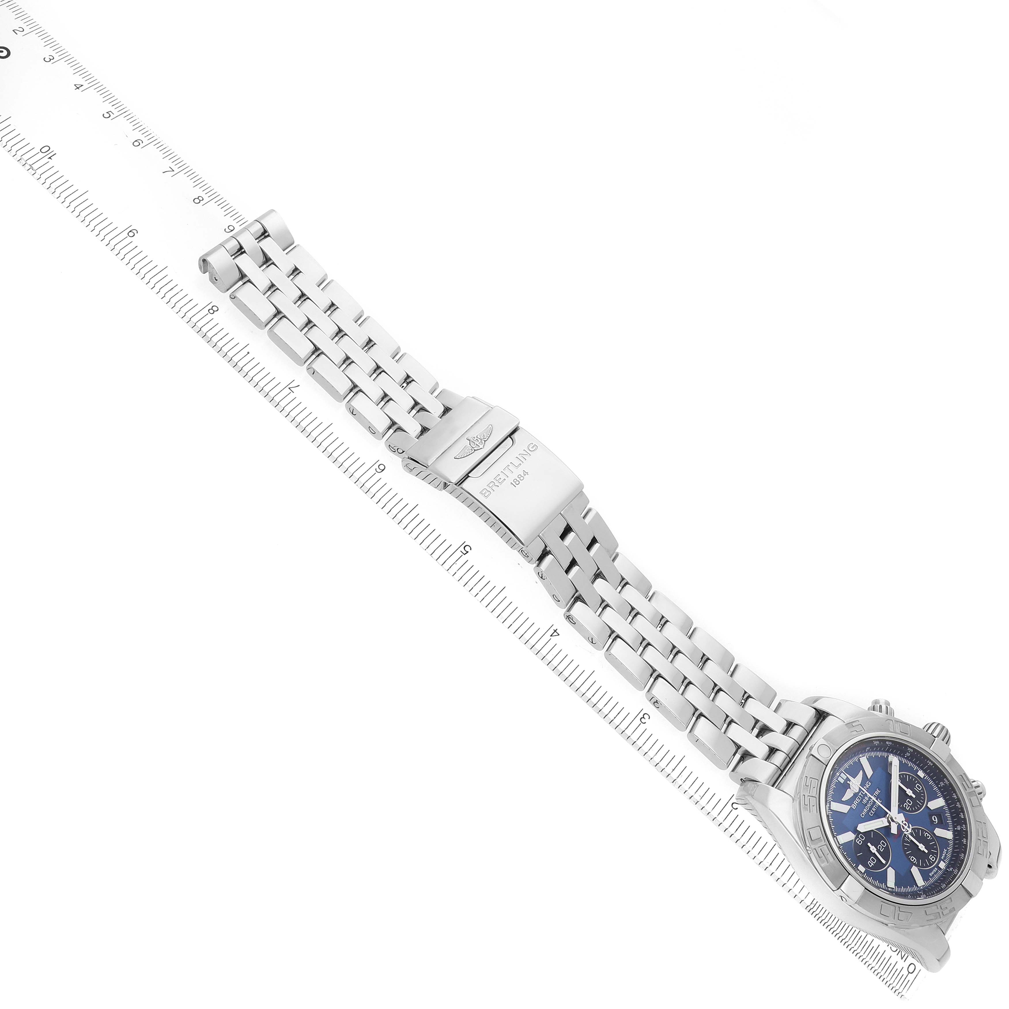 The image shows a Breitling Chronomat AB0110/A011C89PA Men's Stainless Steel Blue Dial watch from an angled side view with its full metal bracelet and clasp, alongside a ruler.