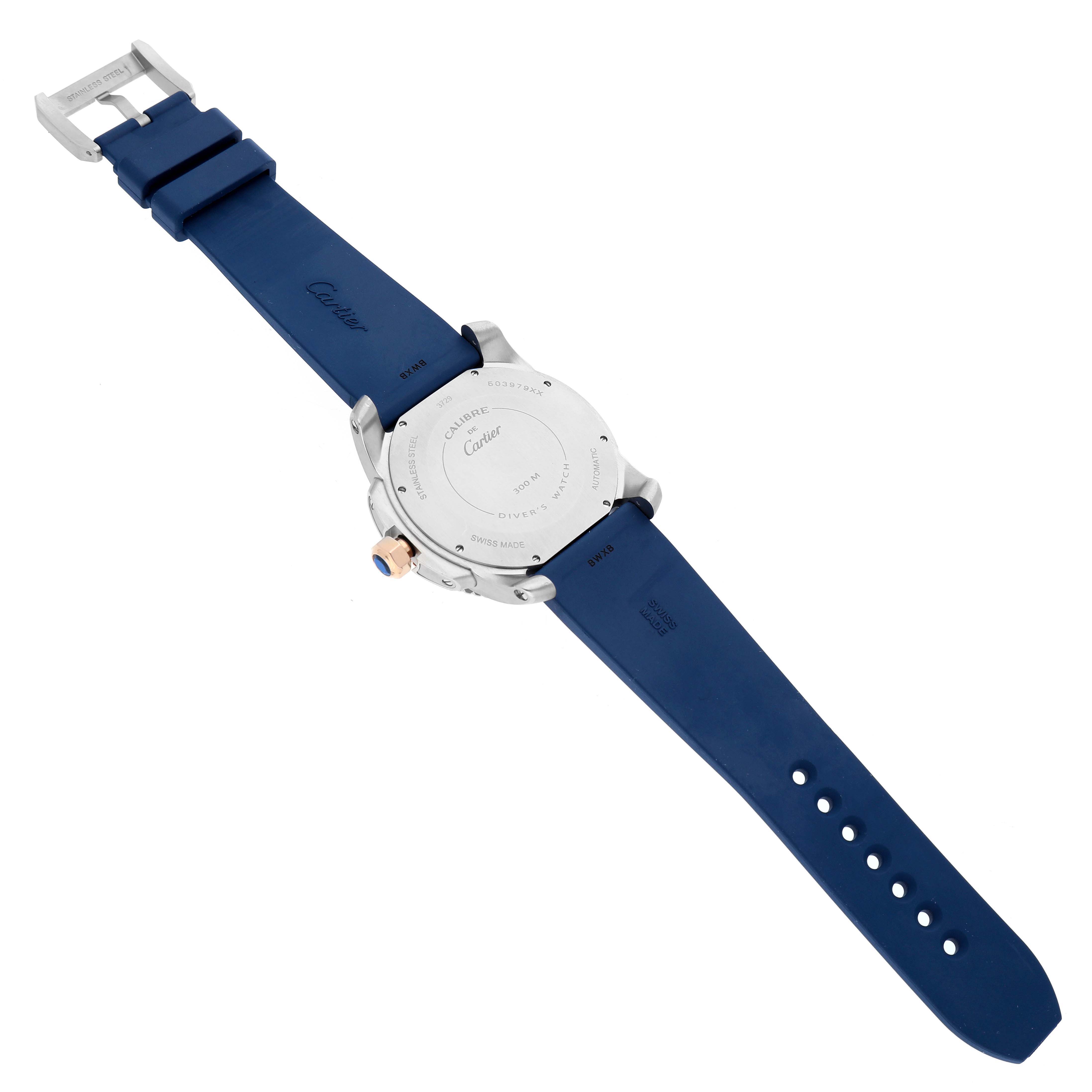 The Calibre de Cartier watch is shown from the back, highlighting the case back, crown, and blue strap.