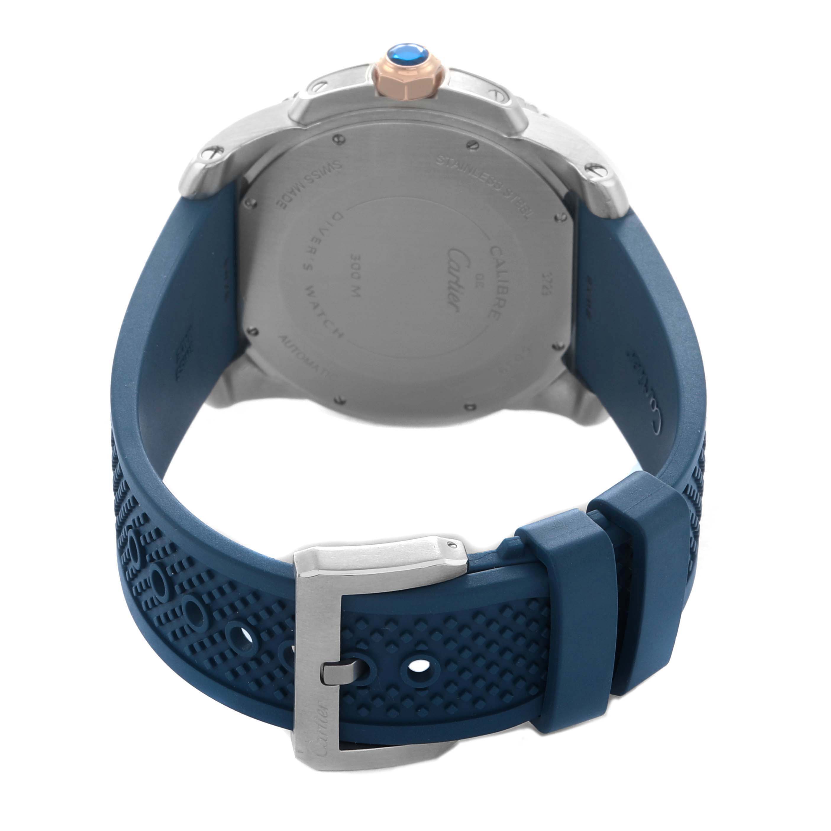 The Calibre de Cartier watch is shown from the back, featuring the case back and a blue rubber strap with a buckle.