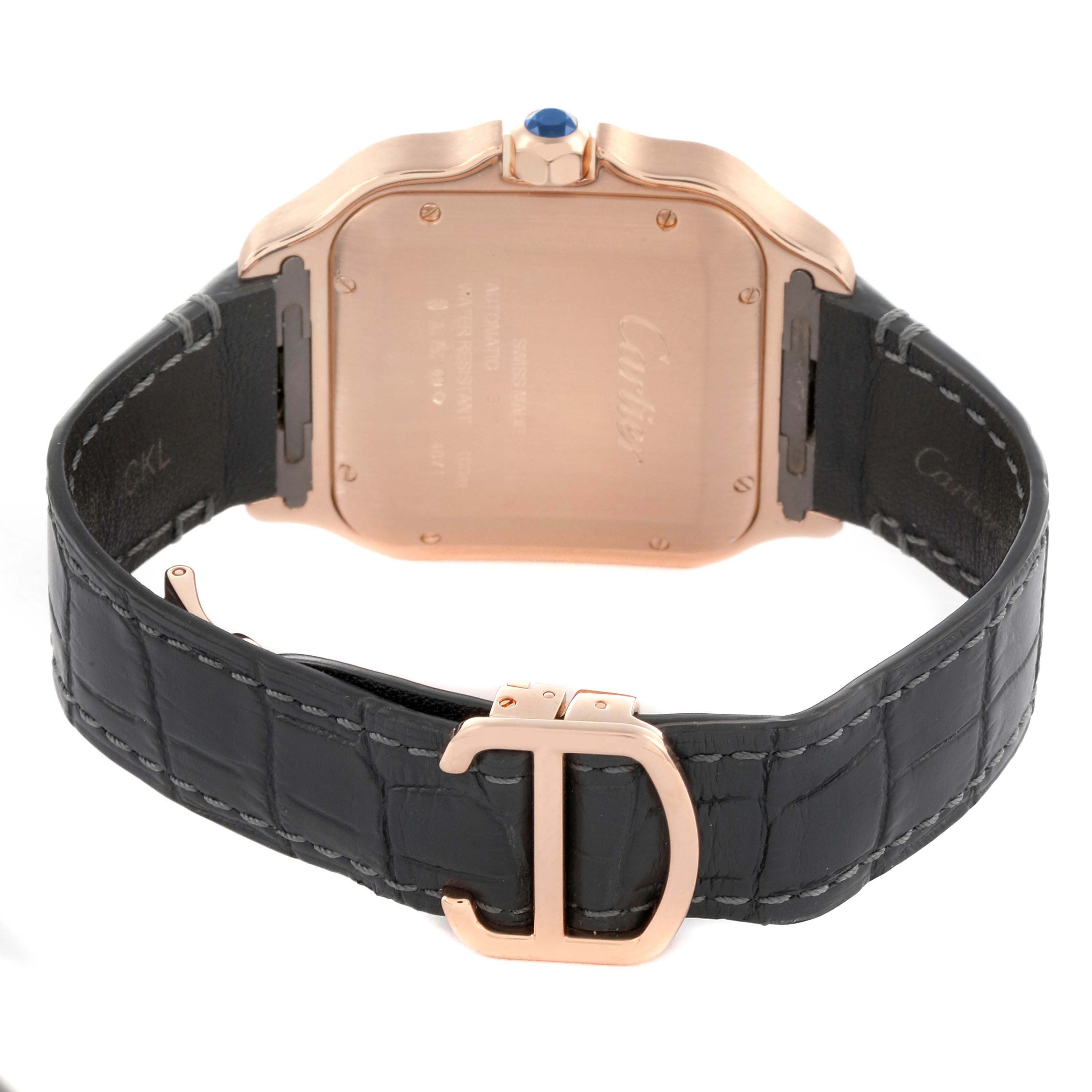 The image shows the back view of the Cartier Santos WGSA0011 Men's Rose Gold Silver Dial watch, highlighting the case back, crown with blue stone, and leather strap with a clasp.