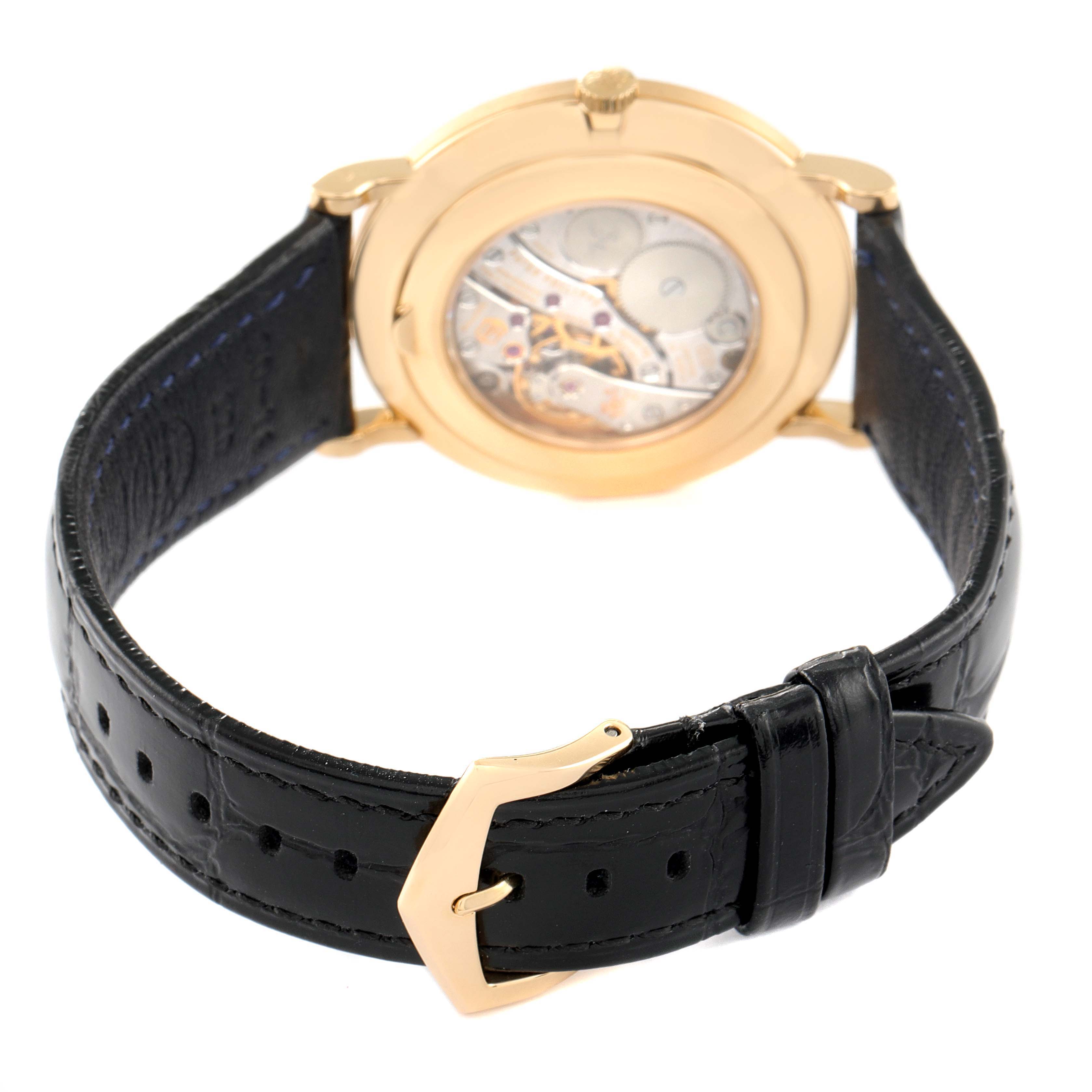 The image shows the back view of a Calatrava model by Patek Philippe, featuring the movement and black leather strap with a buckle.