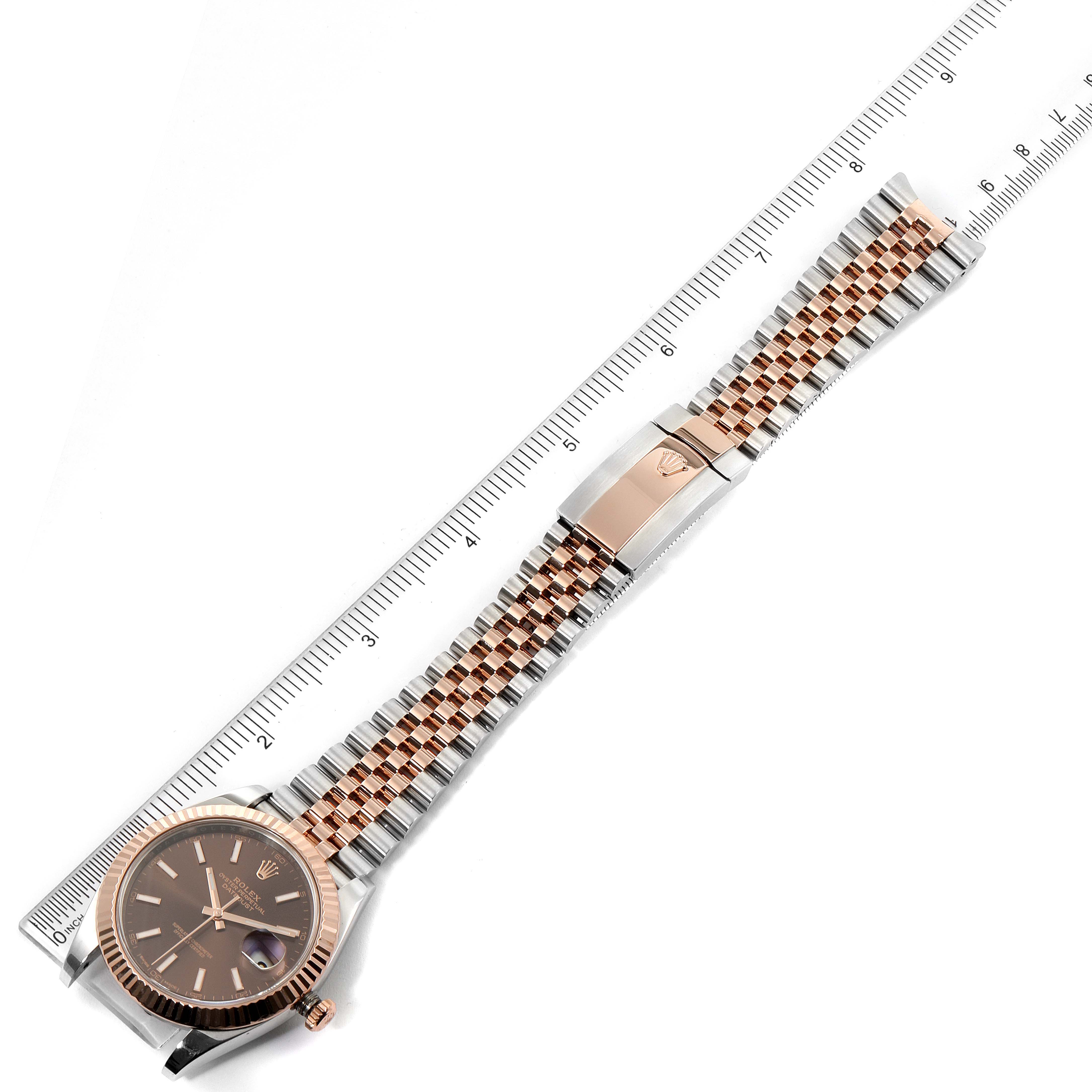 The image shows a Rolex Datejust 41 126331 Men's Steel and Gold (two tone) Brown Dial 126331 Men's Steel and Gold (two tone) Brown Dial watch laid flat with a ruler beside it, displaying the face, bracelet, and clasp.