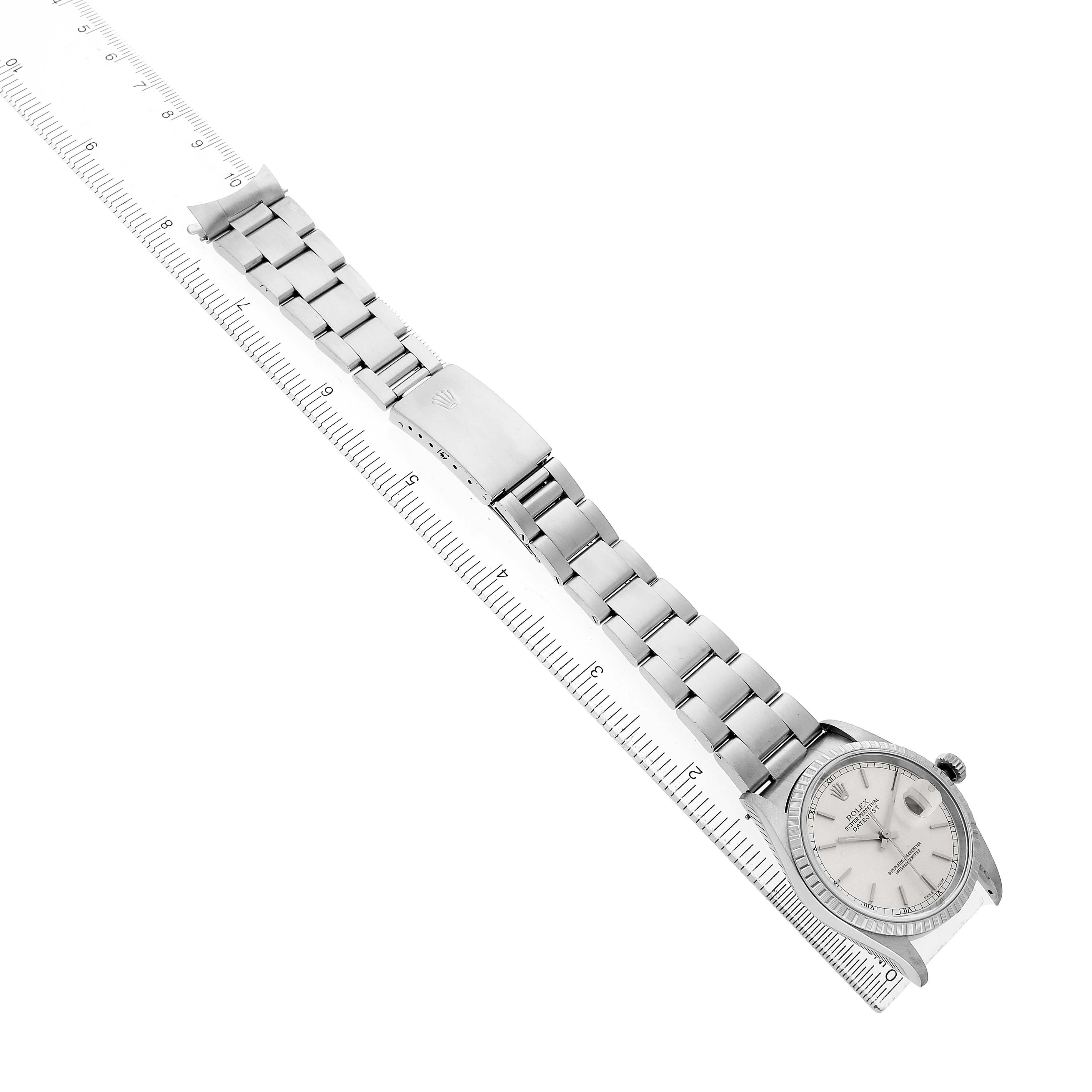 The Rolex Datejust 16220 Men's Stainless Steel Silver Dial watch is shown from a top-down angle, displaying the full bracelet, clasp, and face near a ruler.