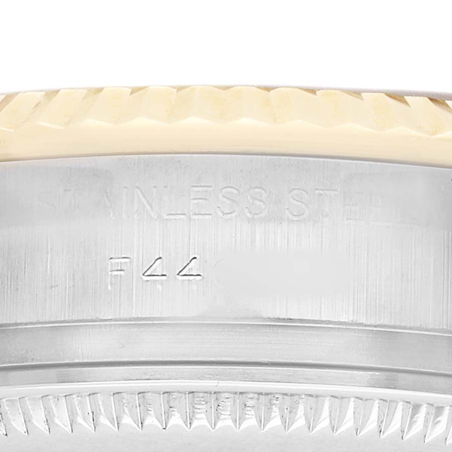 The image shows a close-up side view of the Rolex Datejust 179173 Women's Steel and Gold (two tone) Champagne Dial bezel and part of the case, focusing on the material engraving.