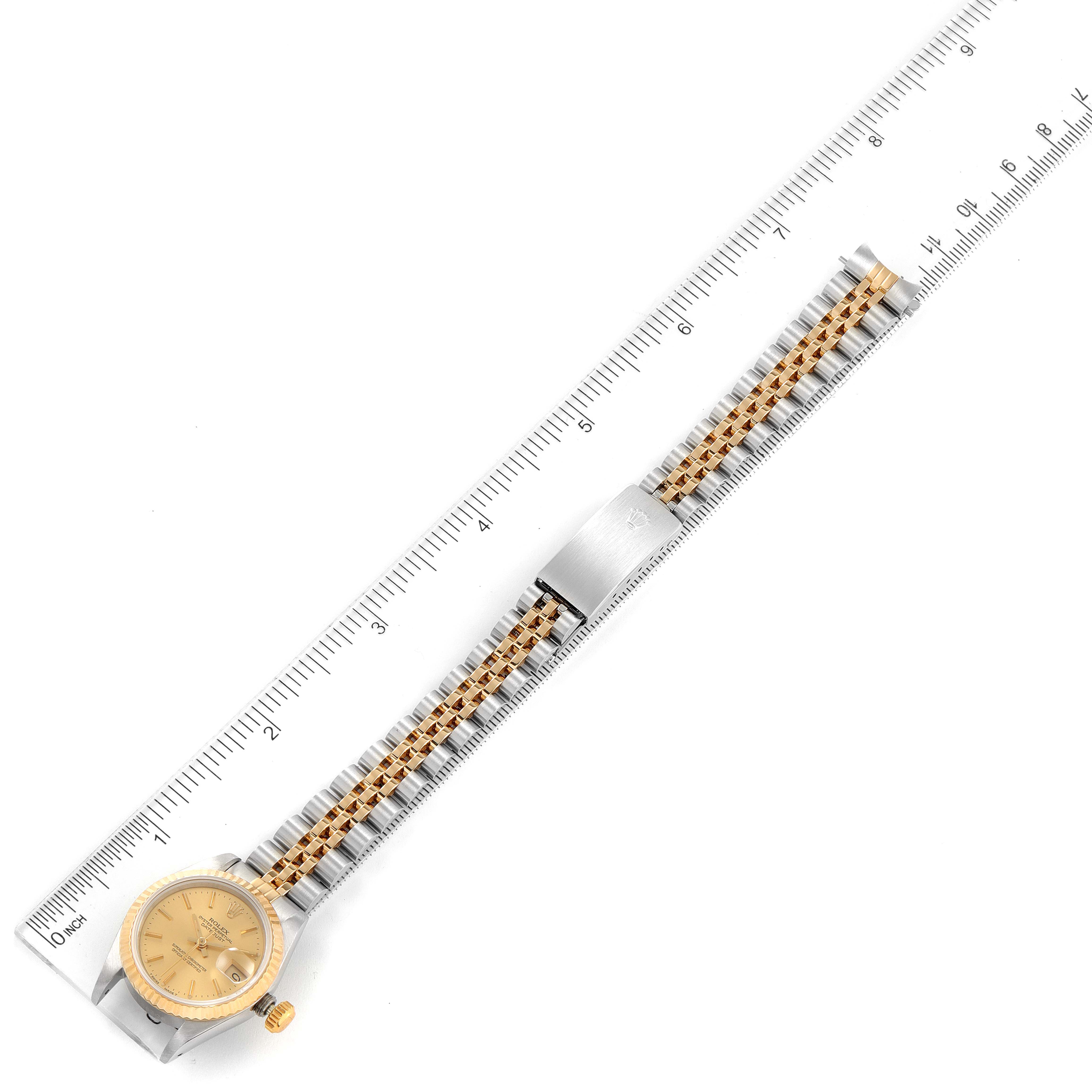 This image shows a Rolex Datejust 69173 Women
s Steel and Gold (two tone) Champagne Dial 69173 Women
s Steel and Gold (two tone) Champagne Dial watch laid flat, with the entire face, bezel, and strap visible alongside a ruler for scale.
