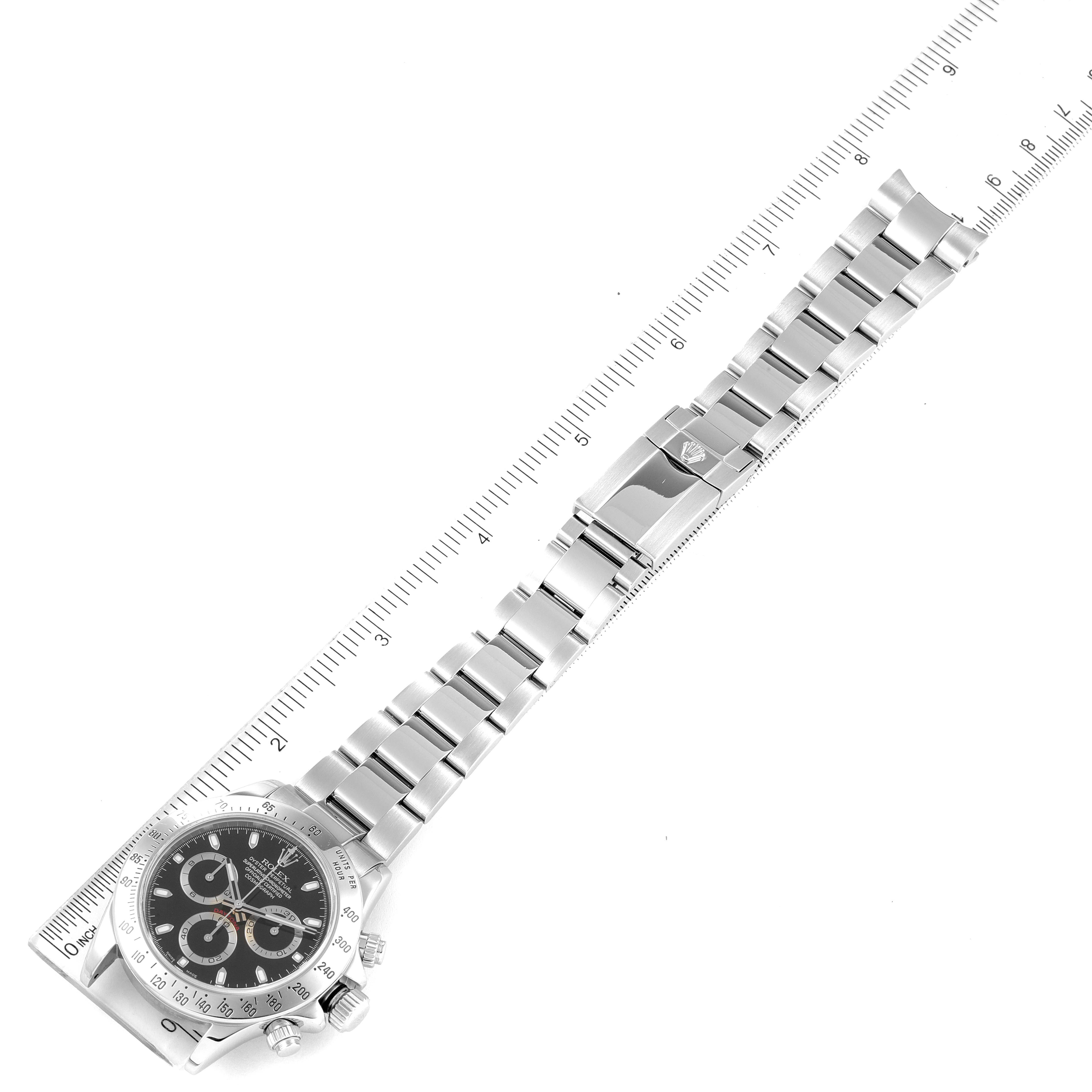 The image shows a Rolex Daytona 116520 Men's Stainless Steel Black Dial 116520 Men's Stainless Steel Black Dial watch laid flat with a ruler, highlighting the bracelet and face at an angle.