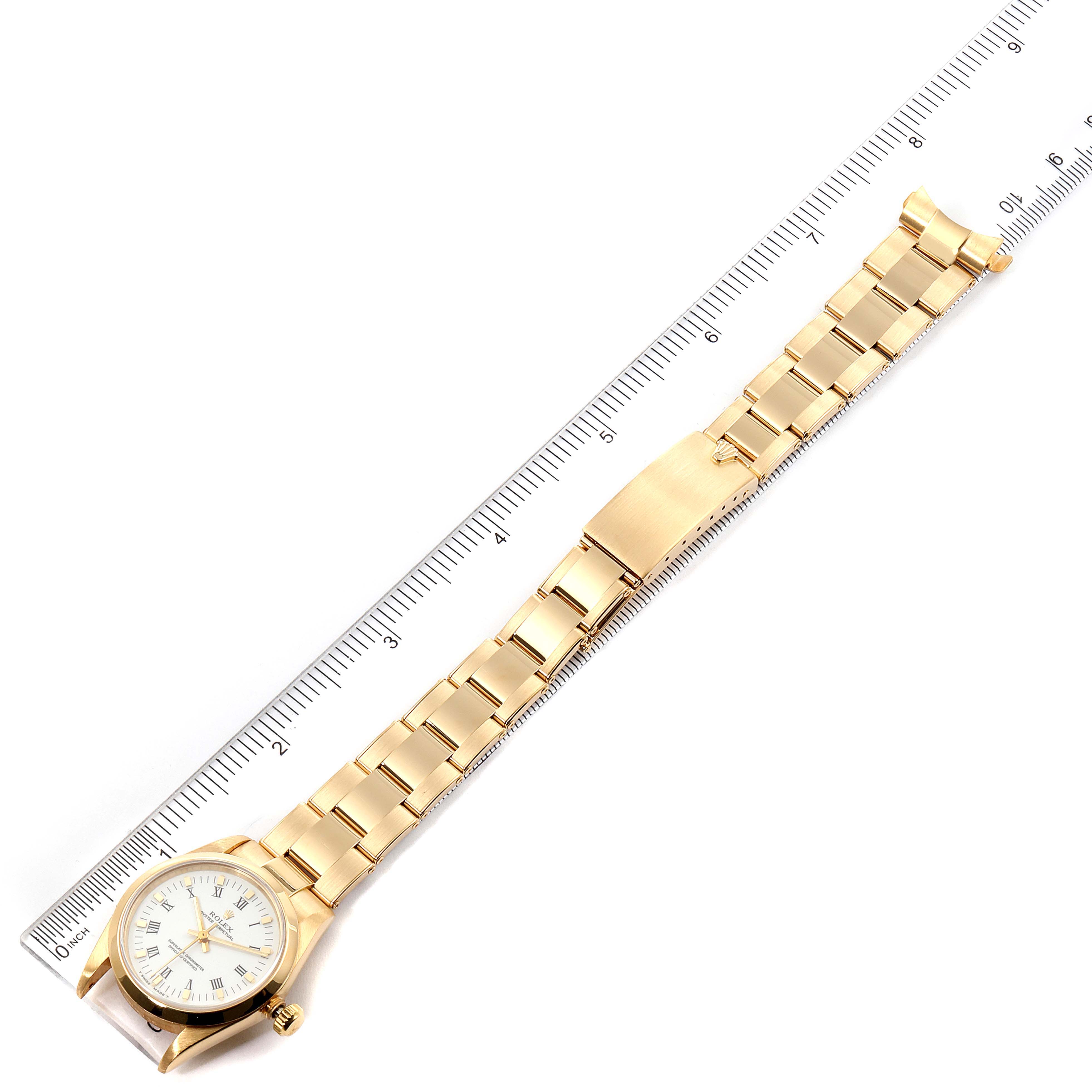 The image shows a President model Rolex watch laid flat, with a ruler measuring the length of its gold band.