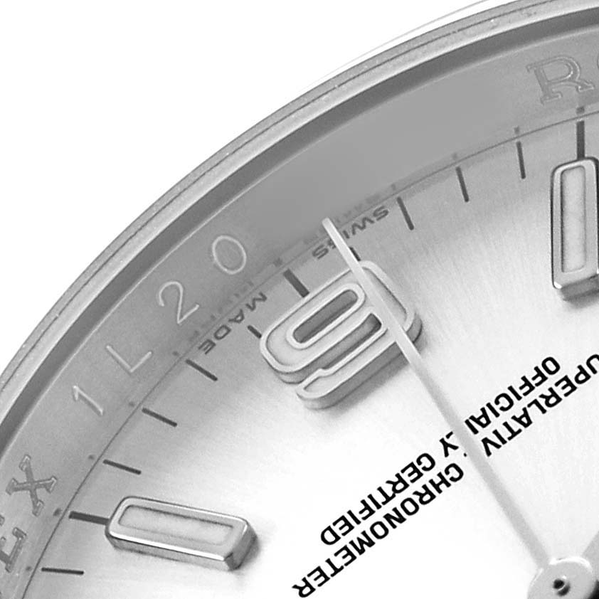 The image shows a close-up of the dial and bezel edge of a Rolex Oyster Perpetual 116000 Men's Stainless Steel Silver Dial, highlighting the hour markers and hands.