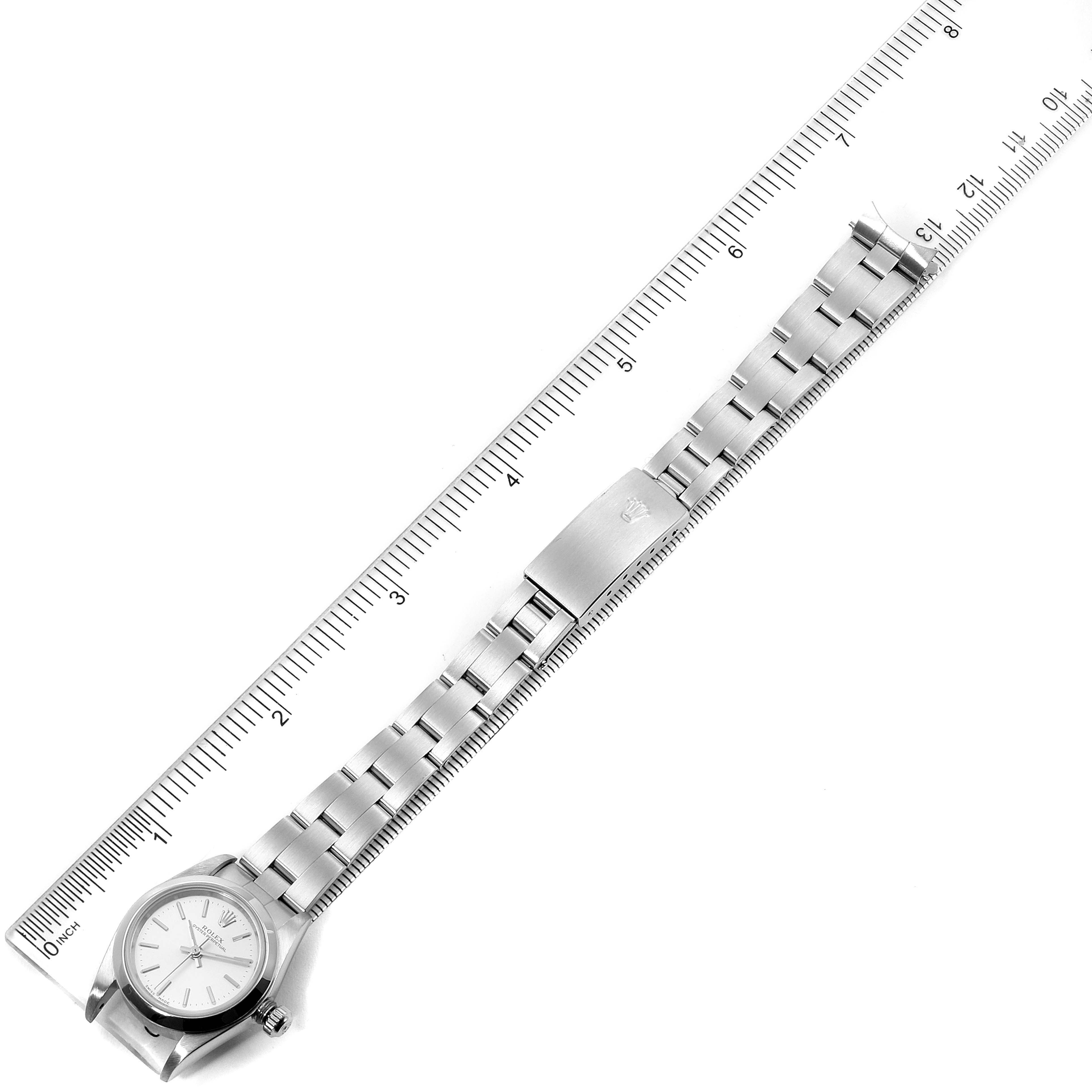 The image shows a top view of a Rolex Oyster Perpetual 76080 Women's Stainless Steel Silver Dial 76080 Women's Stainless Steel Silver Dial watch with its stainless steel bracelet fully extended and a ruler.