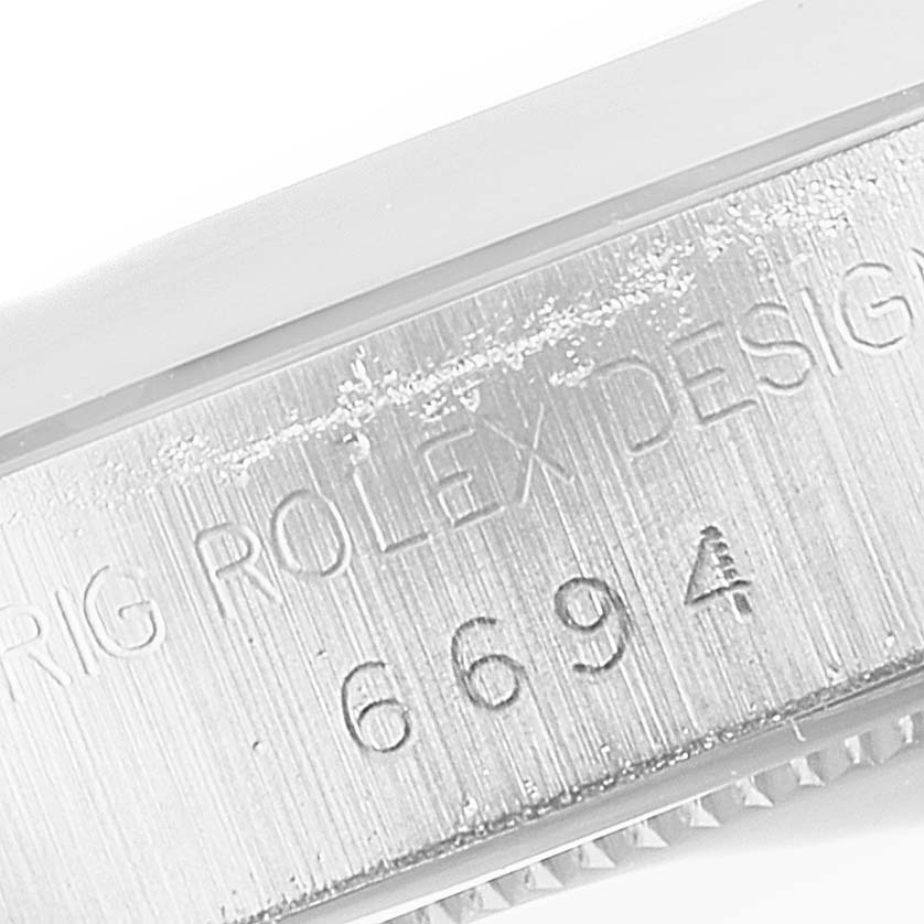 This image shows a close-up of the engraved serial number and "ROLEX DESIGN" text on the side of the Rolex Vintage Collection 6694 Men
s Stainless Steel Silver Dial 6694 Men
s Stainless Steel Silver Dial model.