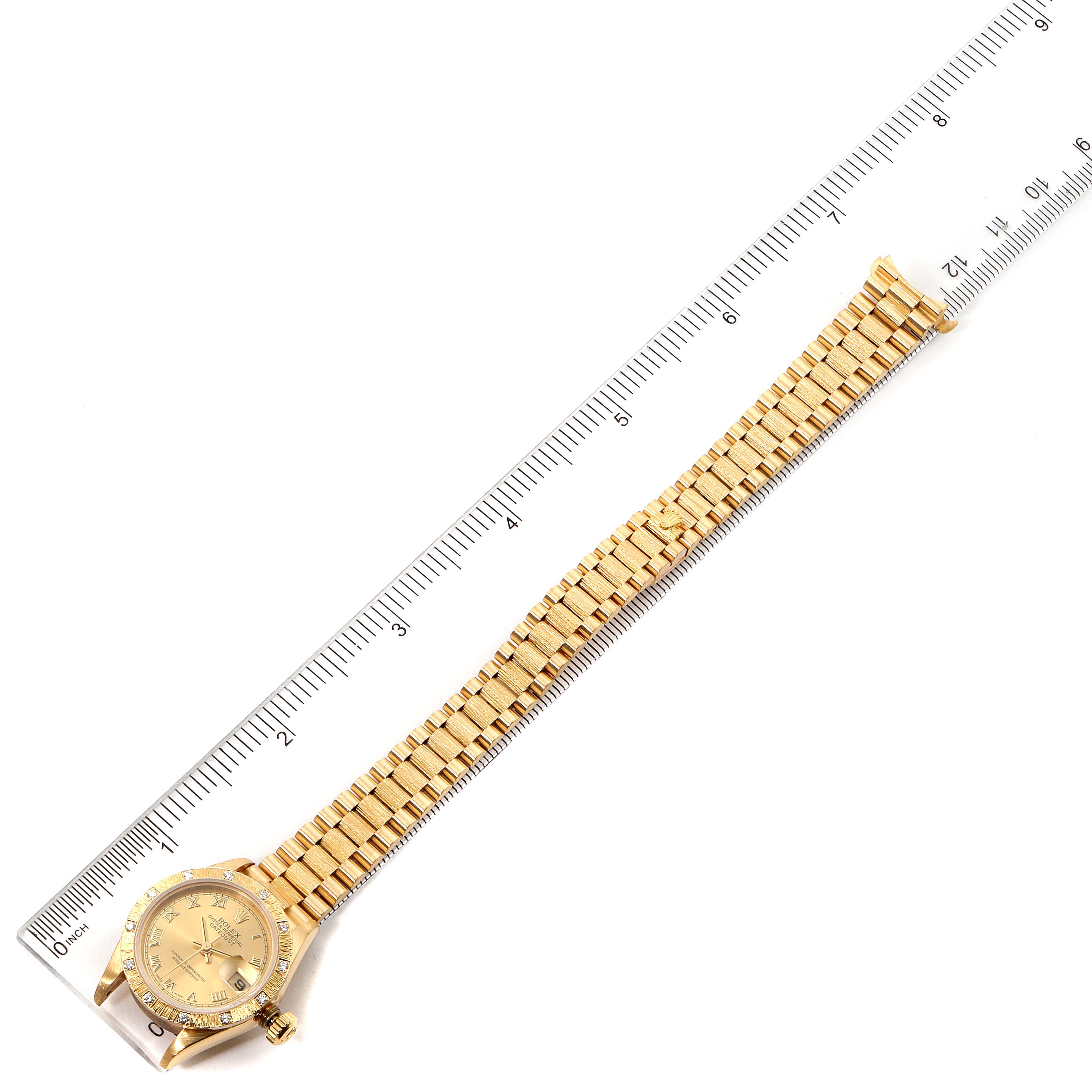 The Rolex President 69288 Women
s Yellow Gold Champagne Dial 69288 Women
s Yellow Gold Champagne Dial model watch is displayed flat with its gold bracelet and face fully visible, alongside a ruler for scale.