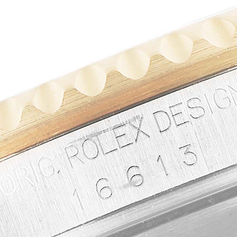 This close-up image shows the side of the bezel and case with inscriptions on a Rolex Submariner 16613 Men's Steel and Gold (two tone) Blue Dial 16613 Men's Steel and Gold (two tone) Blue Dial model.