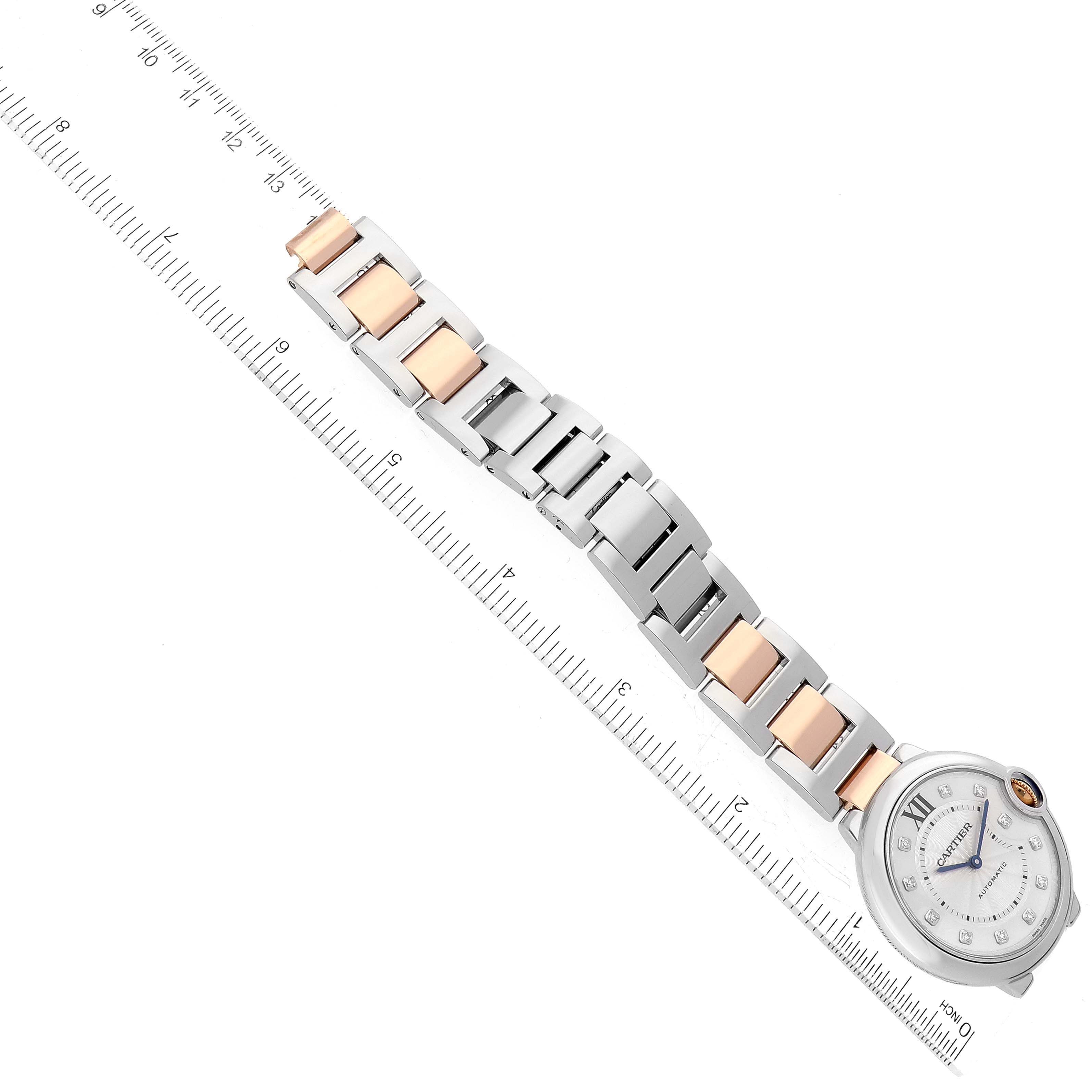The image shows a Ballon Bleu by Cartier watch with stainless steel and rose gold bracelet links, placed next to a ruler for scale.
