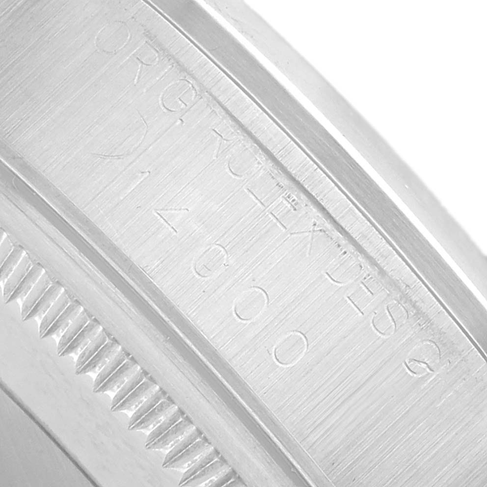 The image shows a close-up of the engraved edge and side of the bezel of a Rolex Oyster Perpetual 14000 Men's Stainless Steel Black Dial watch.