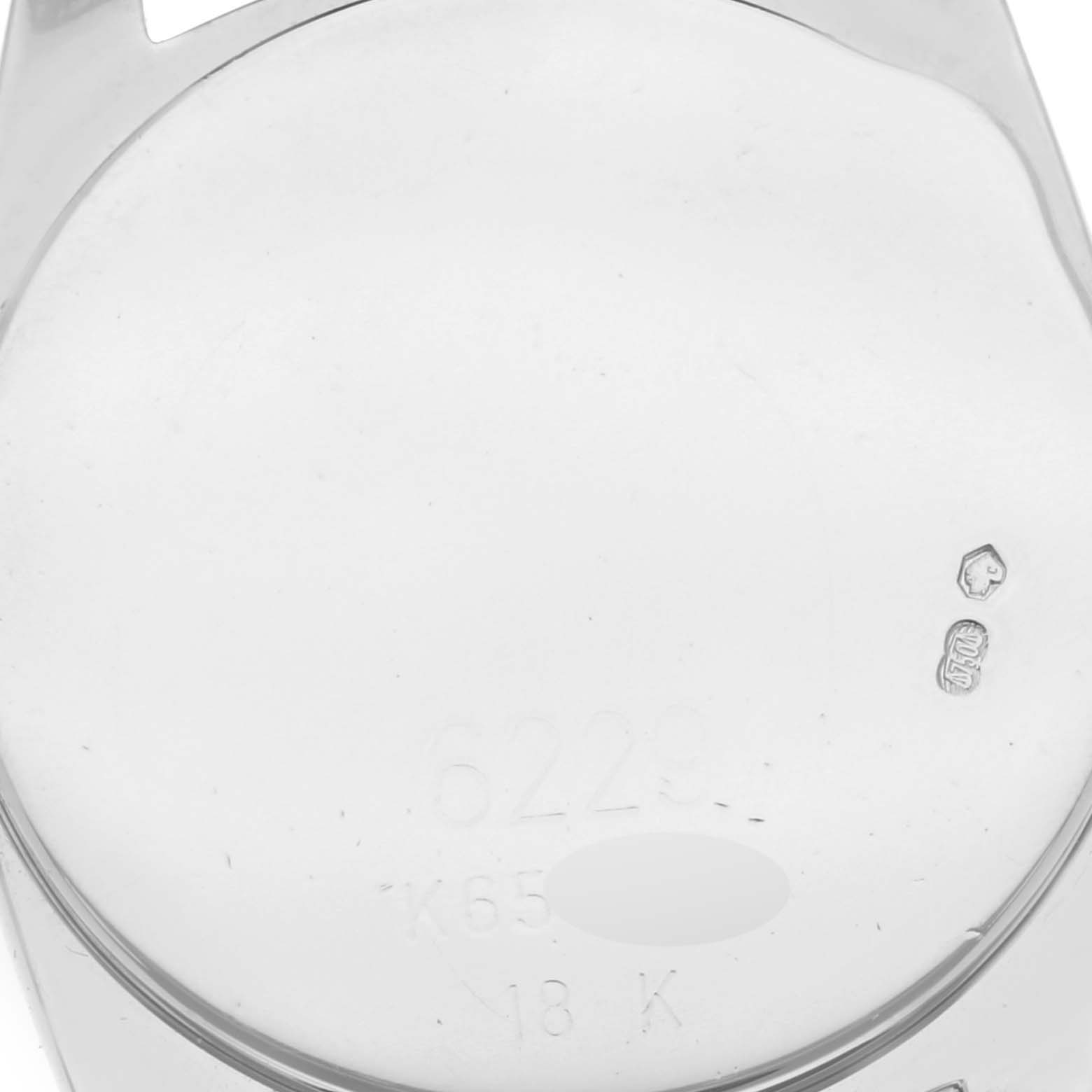 This image shows the reverse side of a Rolex Cellini 6229 Women's White Gold White Dial 6229 Women's White Gold White Dial watch case with hallmark engravings.