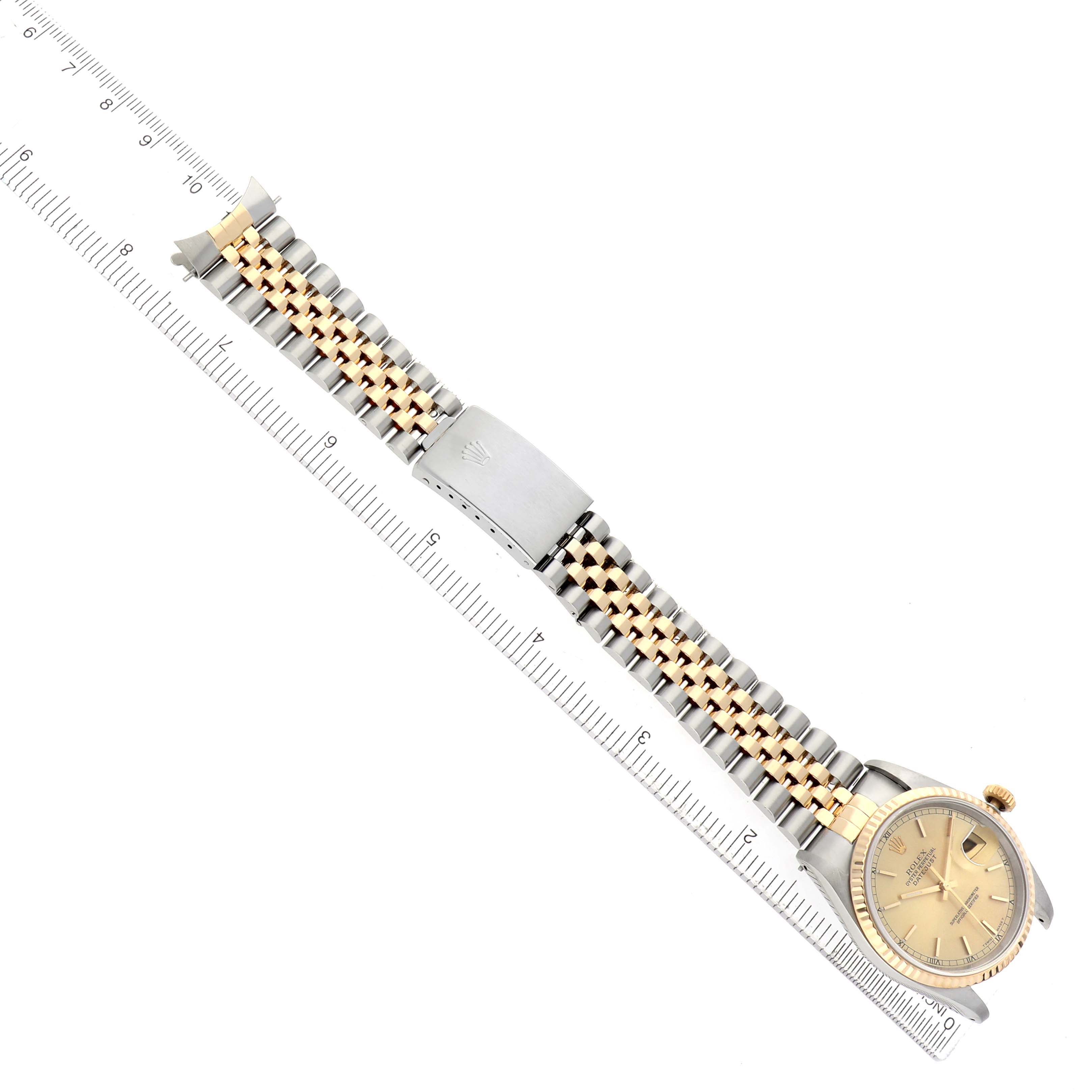 The image shows the Rolex Datejust 16233 Men's Steel and Gold (two tone) Champagne Dial at a top-down angle, highlighting the jubilee bracelet, clasp, and watch face next to a ruler.