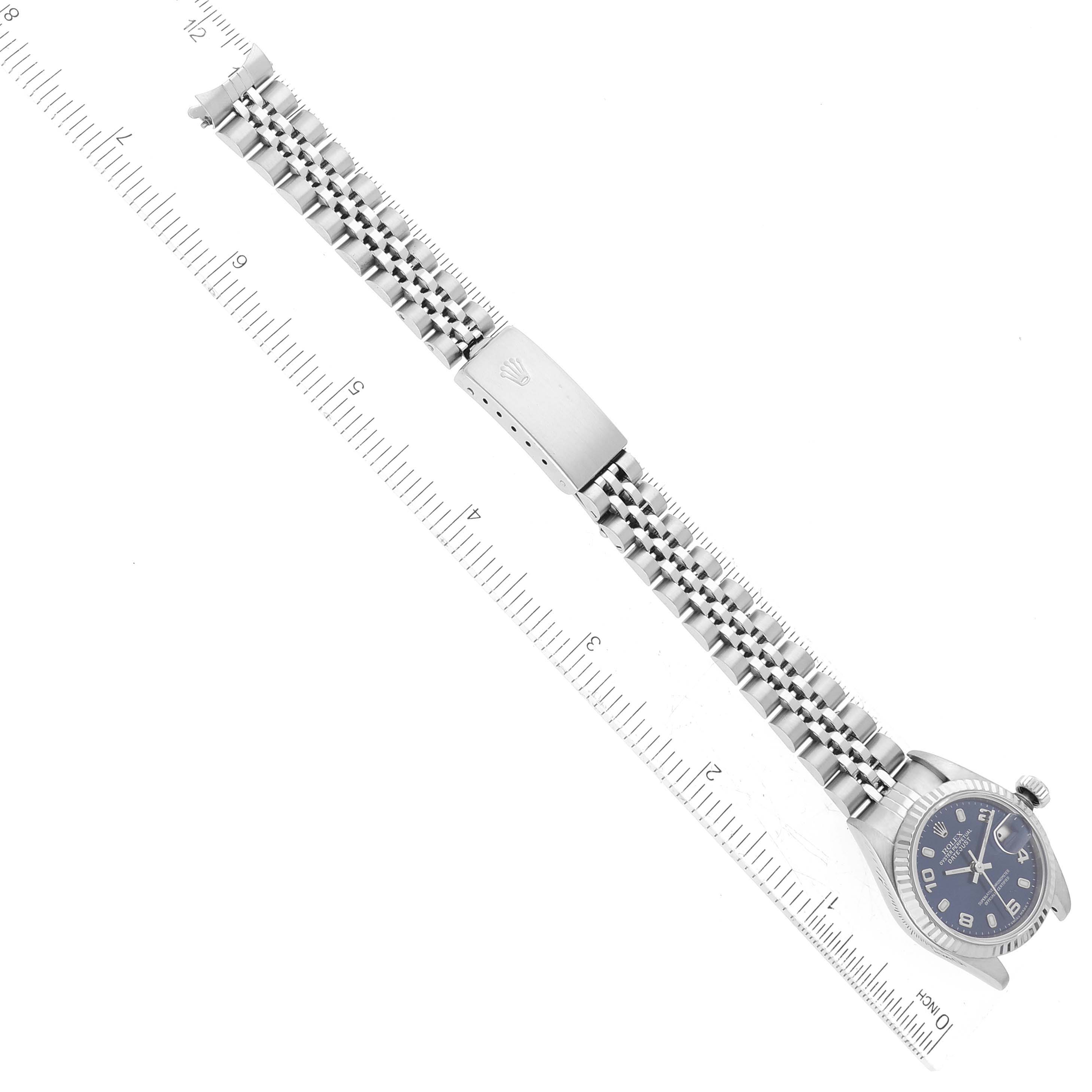 The image shows a Rolex Datejust 79174 Women's Stainless Steel Blue Dial 79174 Women's Stainless Steel Blue Dial watch laid flat with its bracelet and clasp, placed beside a ruler for scale.