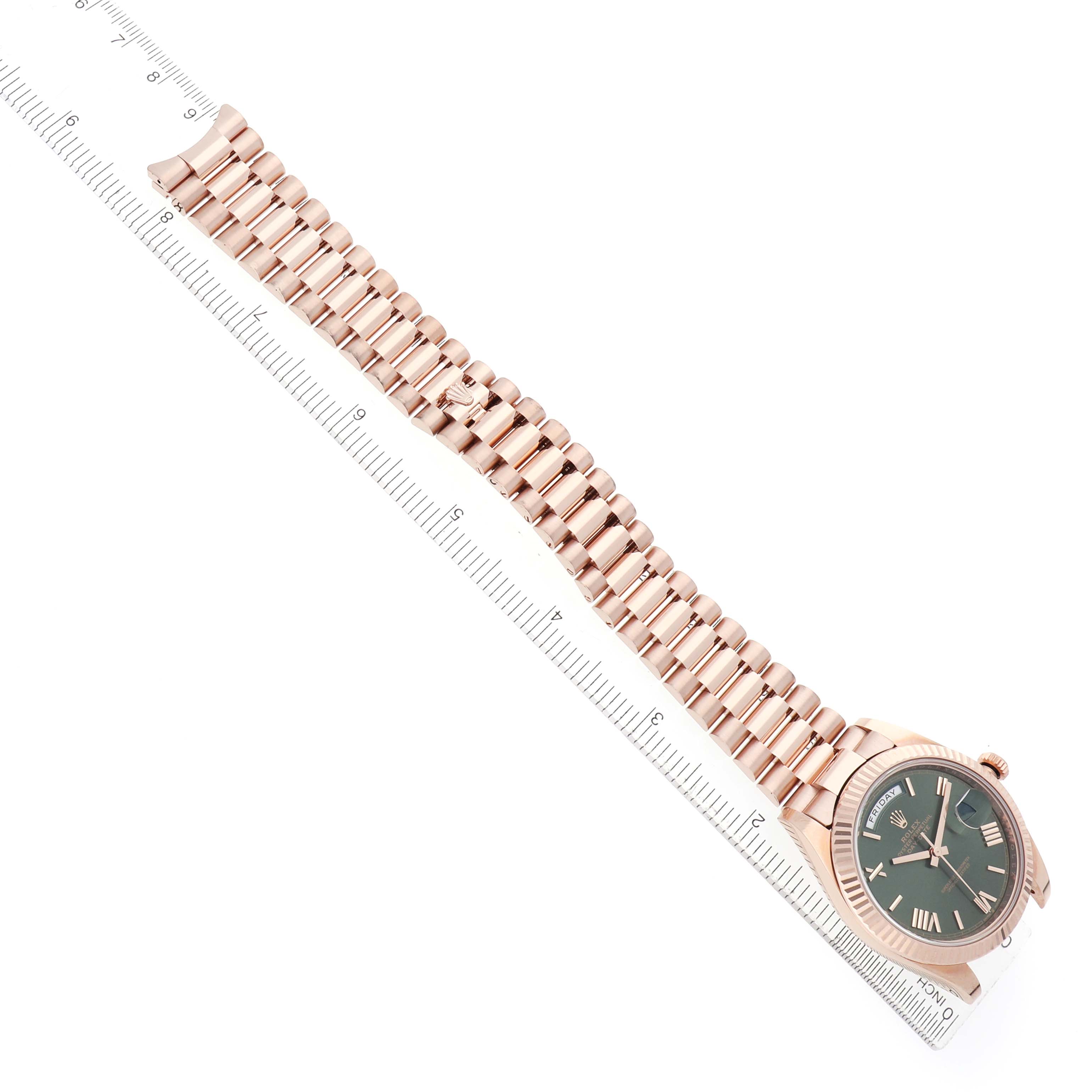 The Rolex President 228235 Men's Rose Gold Green Dial model watch is shown from a top-down angle, displaying its face and full bracelet alongside a ruler.