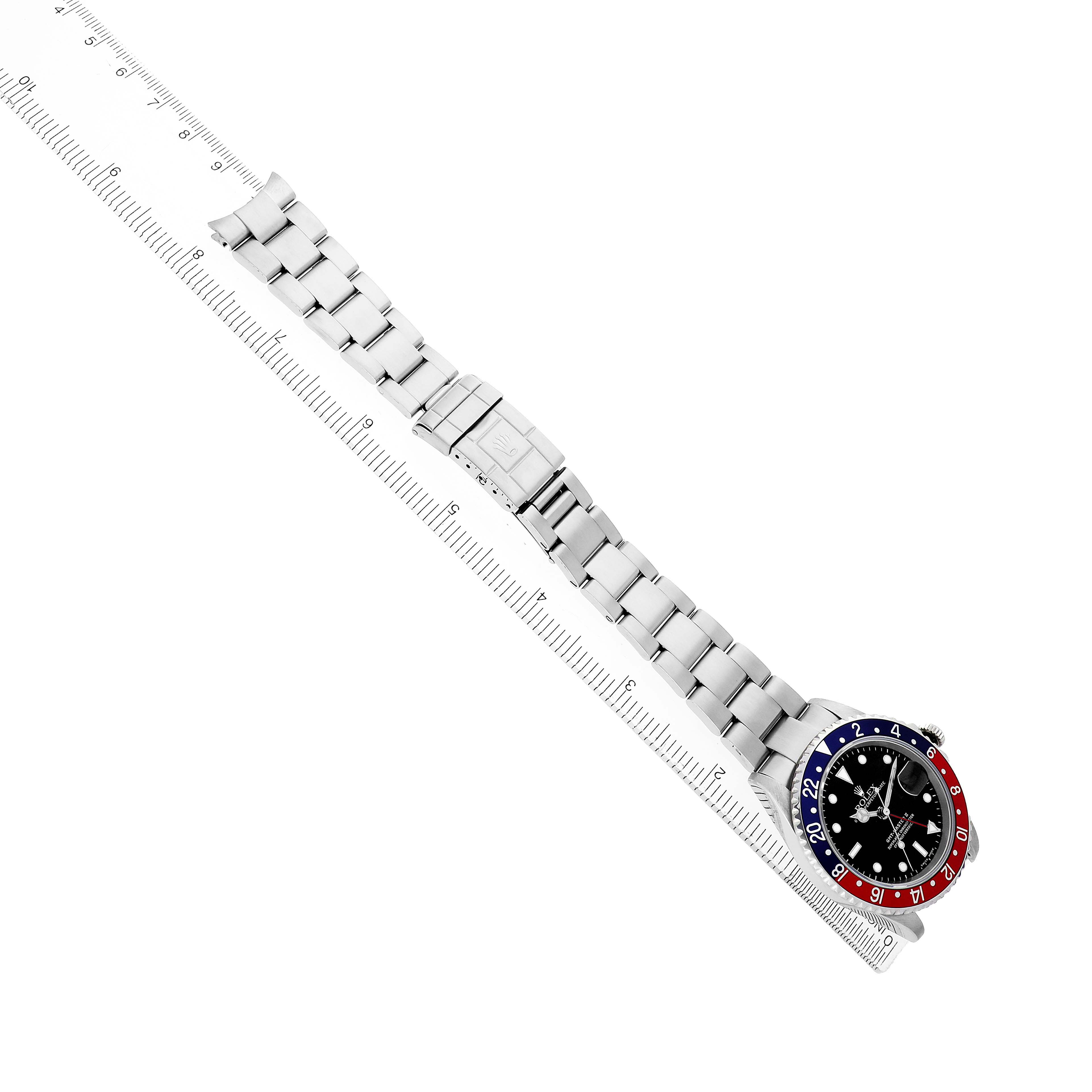 The Rolex GMT-Master 16710 Men's Stainless Steel Black Dial watch is shown flat with a ruler, displaying its full bracelet and face angled to the right.