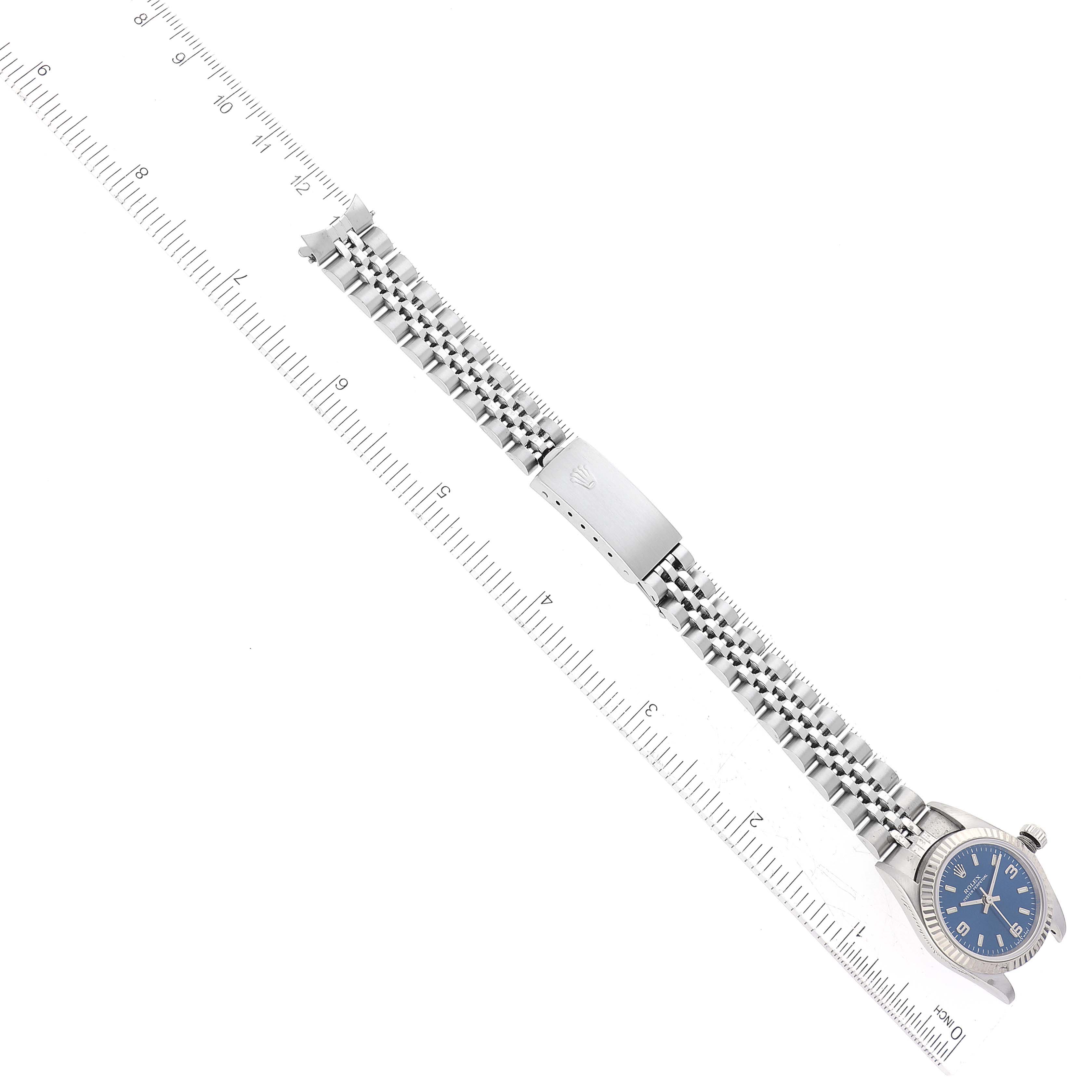 This image shows a side angle of a Rolex Oyster Perpetual 76094 Women's Stainless Steel Blue Dial 76094 Women's Stainless Steel Blue Dial watch with its full metal strap alongside a measuring ruler.