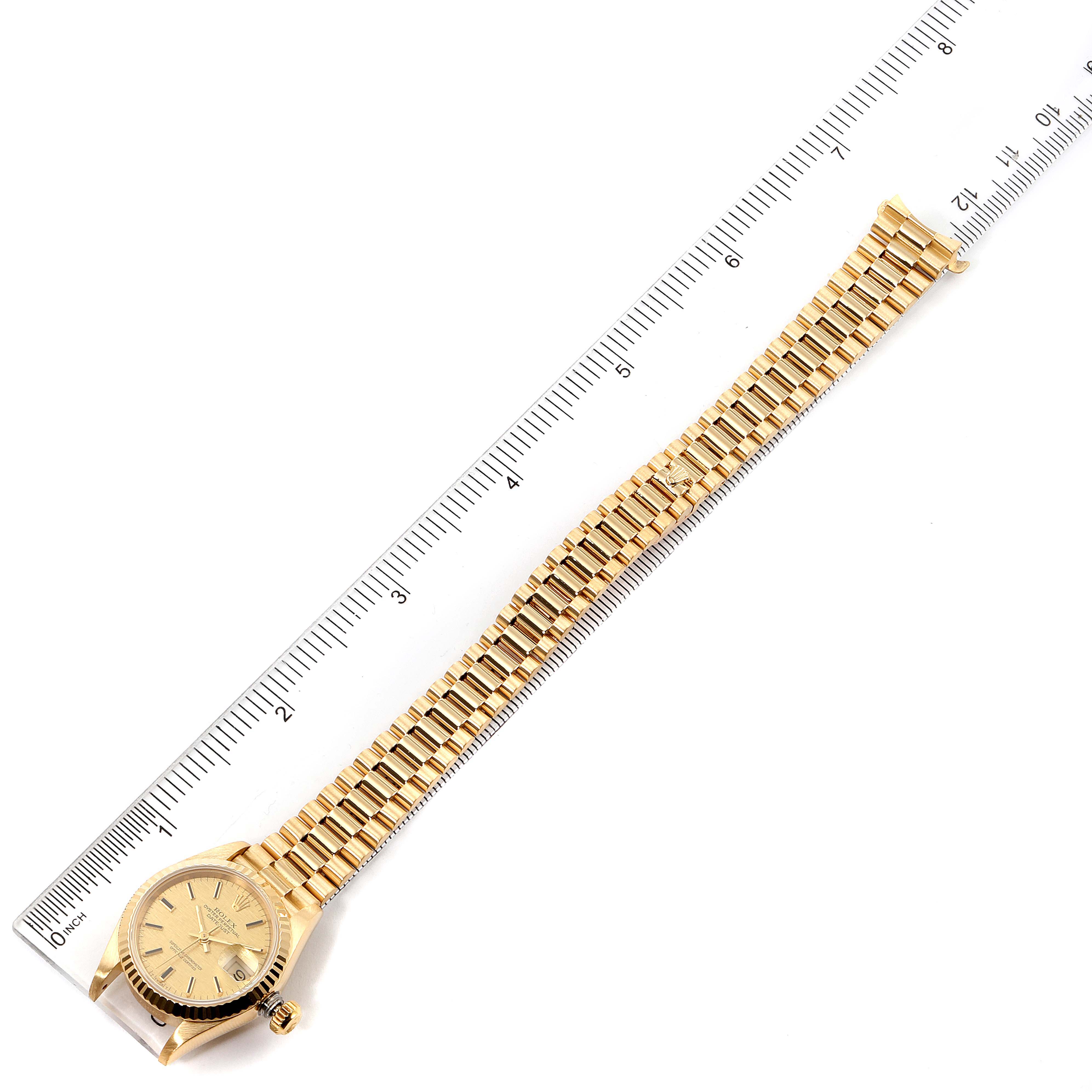 This image shows a bird's-eye view of a Rolex President 69178 Women's Yellow Gold Champagne Dial 69178 Women's Yellow Gold Champagne Dial model watch, including the dial, bezel, crown, and bracelet, aligned next to a ruler.