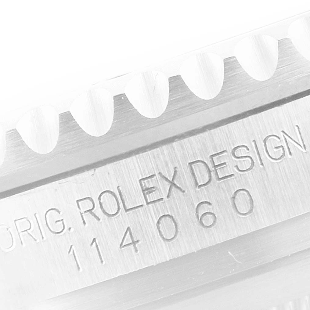 The image shows a close-up of the engraved case side of a Rolex Submariner 114060 Men
s Stainless Steel Black Dial 114060 Men
s Stainless Steel Black Dial watch, specifically detailing the model number and "ROLEX DESIGN".
