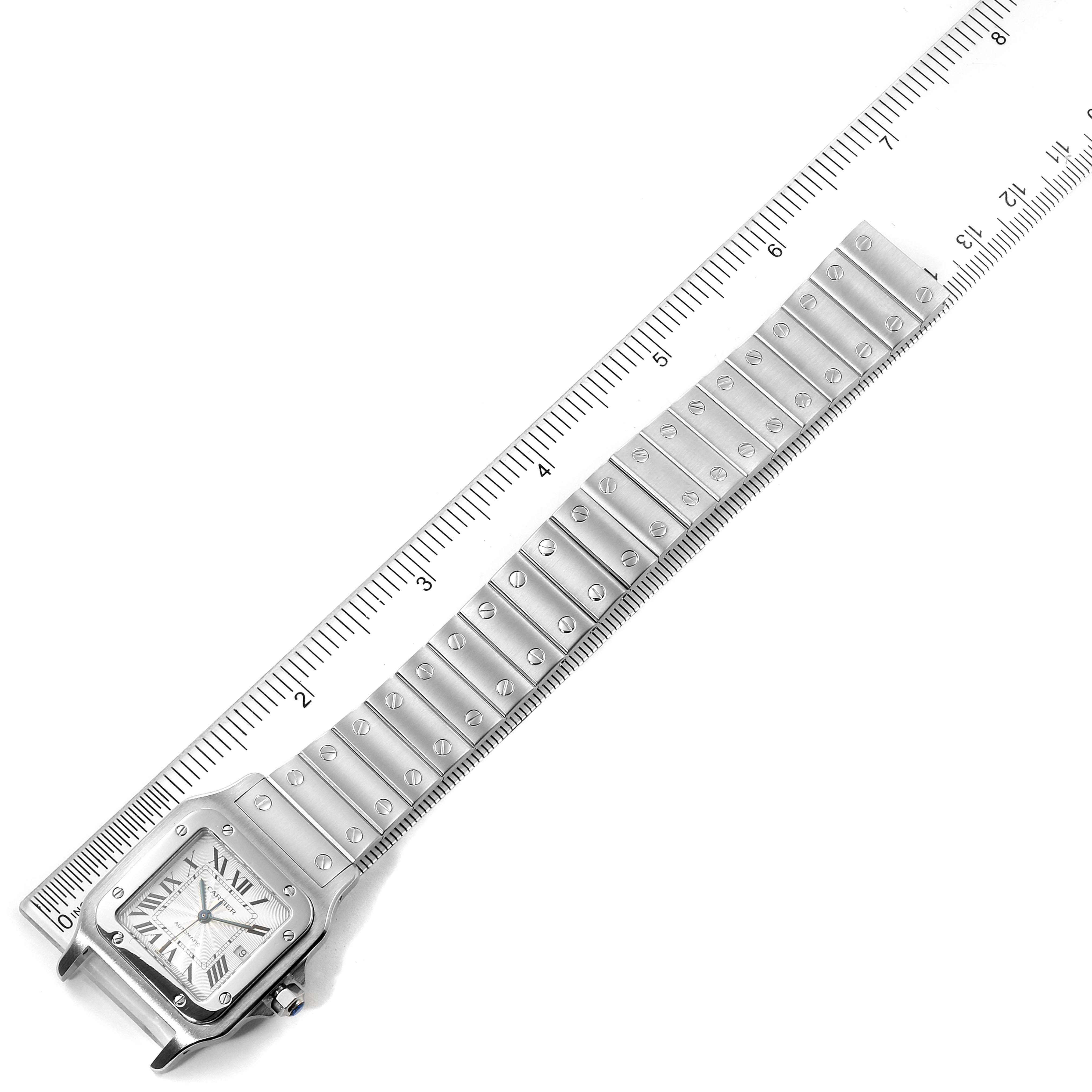 The Cartier Santos W20055D6 Men's Stainless Steel Silver Dial W20055D6 Men's Stainless Steel Silver Dial watch is shown flat with a view of the dial, bracelet, and scale ruler for measurement.