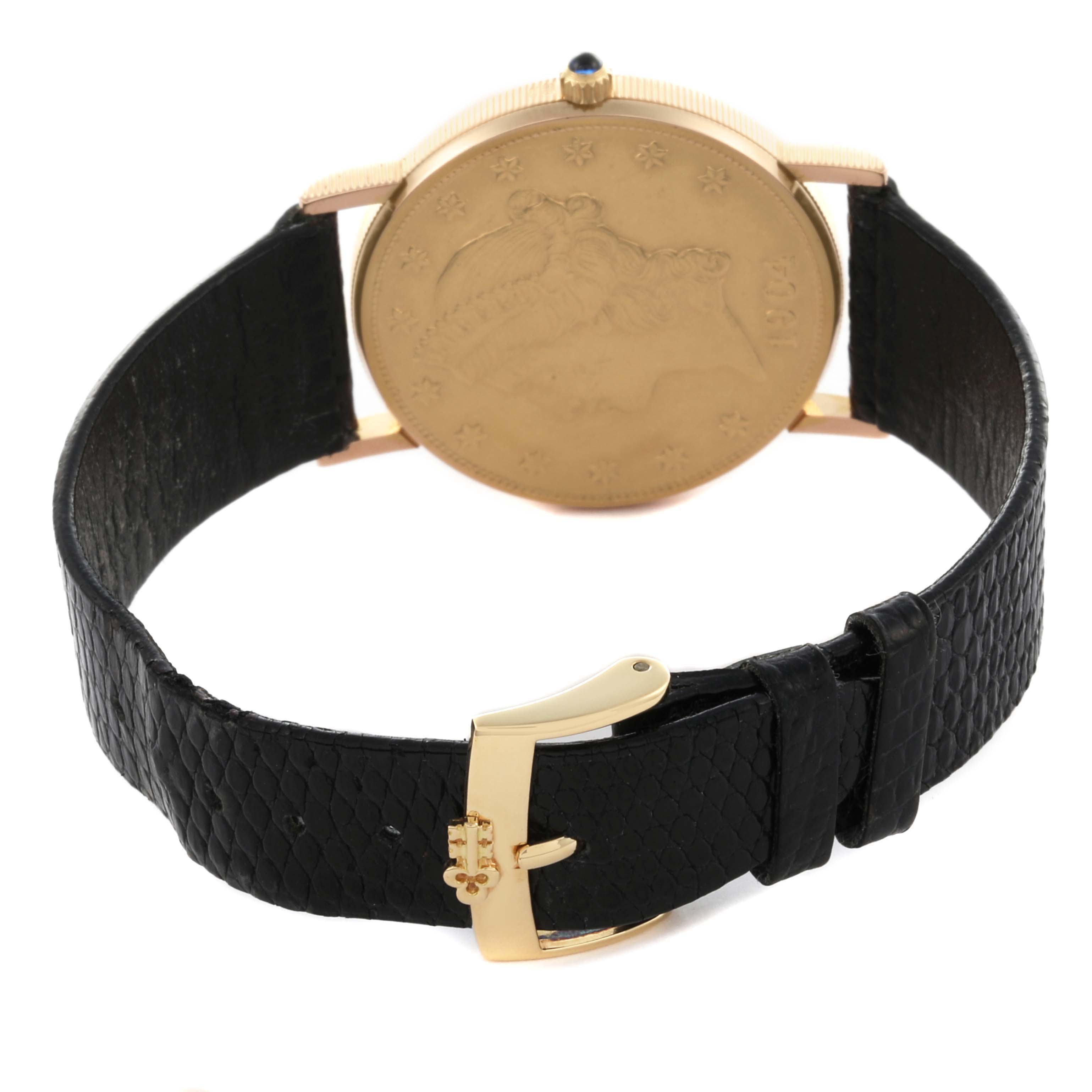 The image shows the back of a Corum Coin Watch Men's Yellow Gold Champagne Dial Men's Yellow Gold Champagne Dial with its black leather strap and gold buckle displayed.
